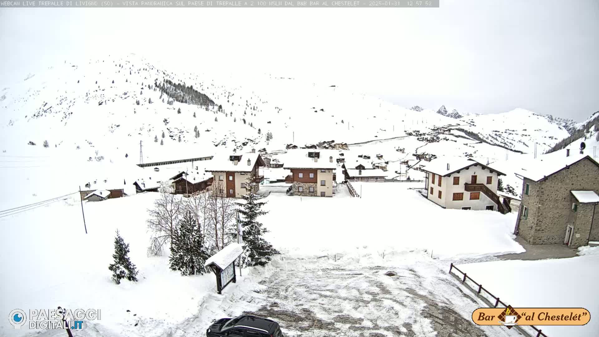 A snow-covered village nestled in a mountainous region under an overcast sky.