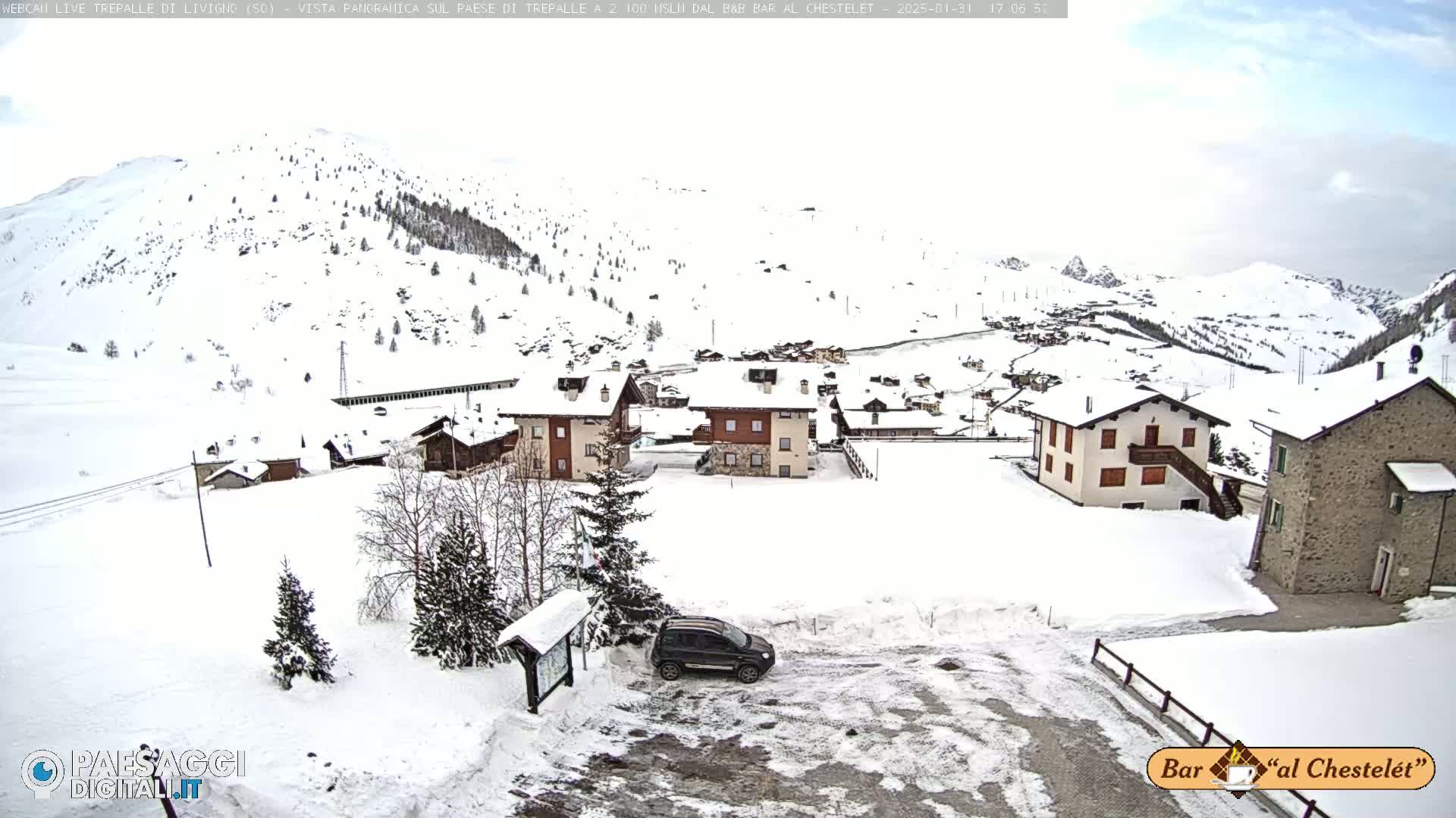 A snow-covered village nestled in a mountainous region under an overcast sky.