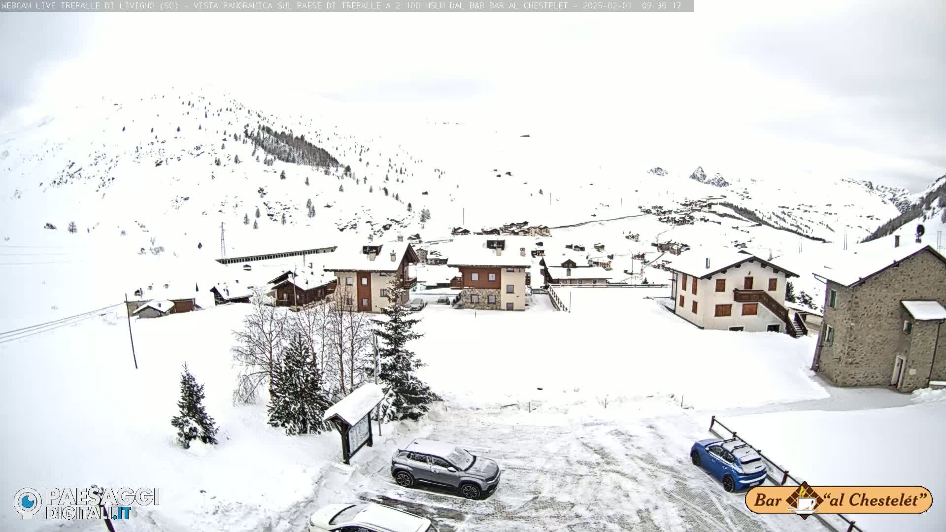 A snow-covered village nestled in a mountainous region under an overcast sky.