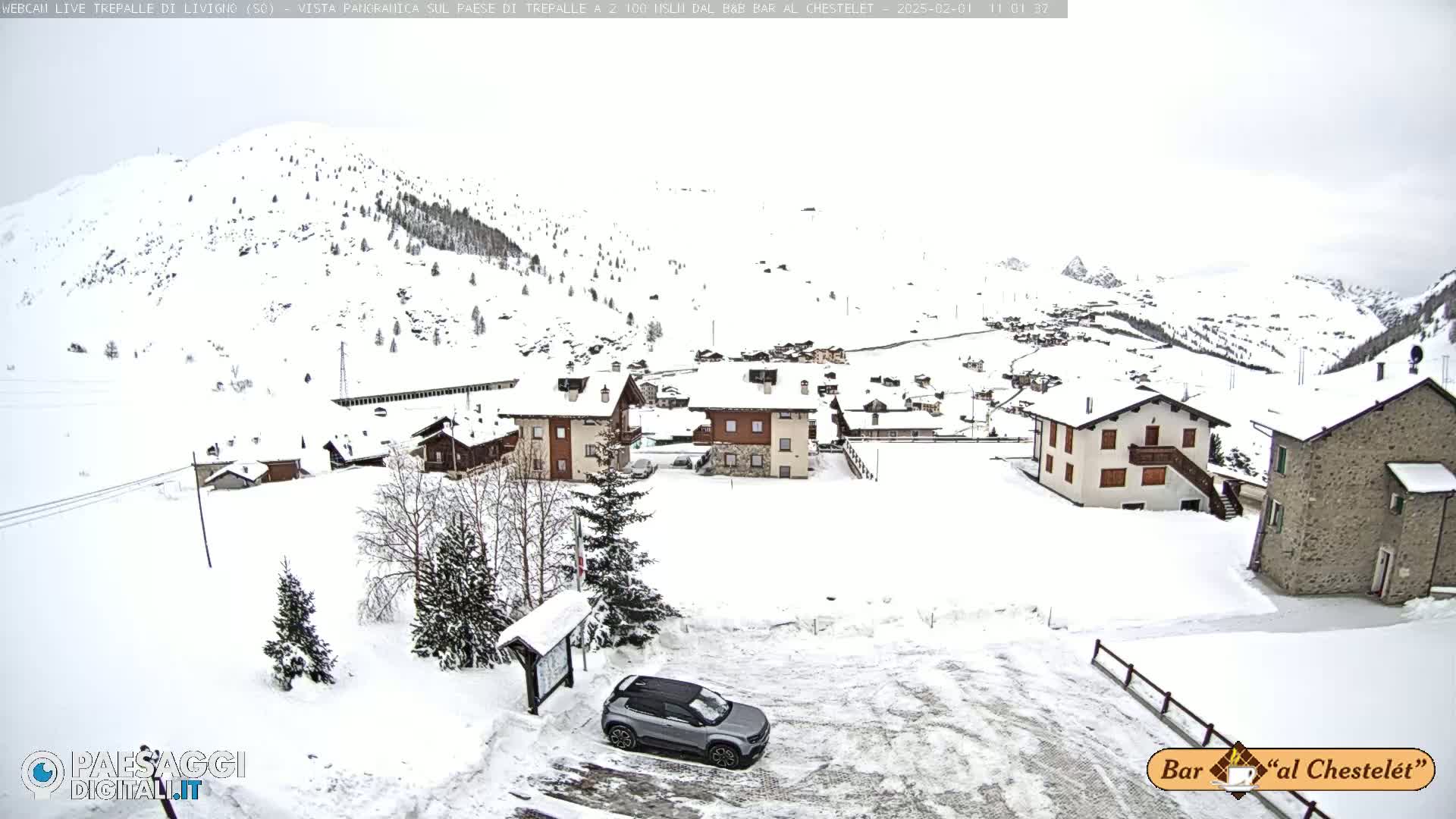 A snow-covered village nestled in a mountainous region under an overcast sky.