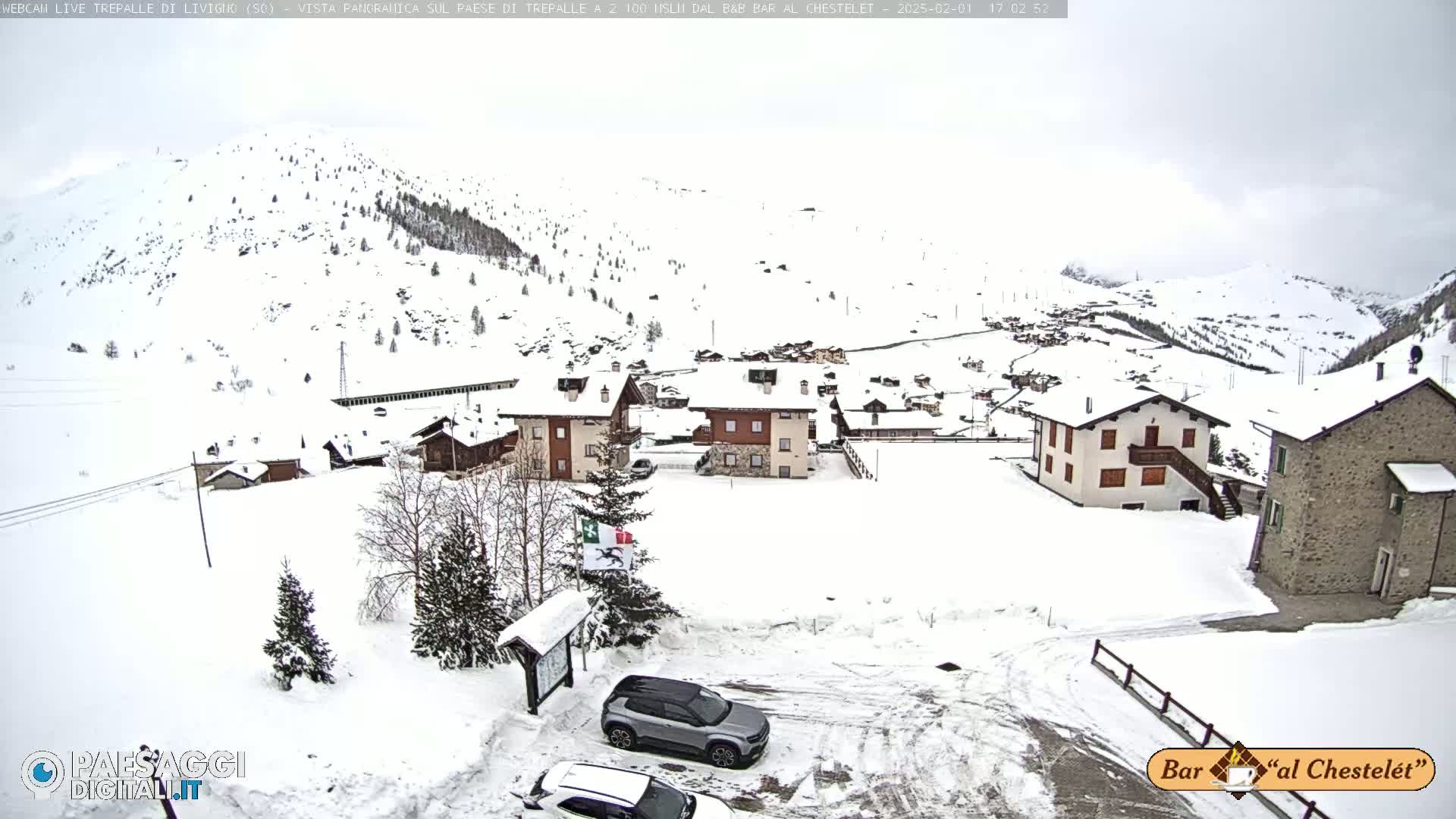 A snow-covered village nestled in a mountainous region under an overcast sky.