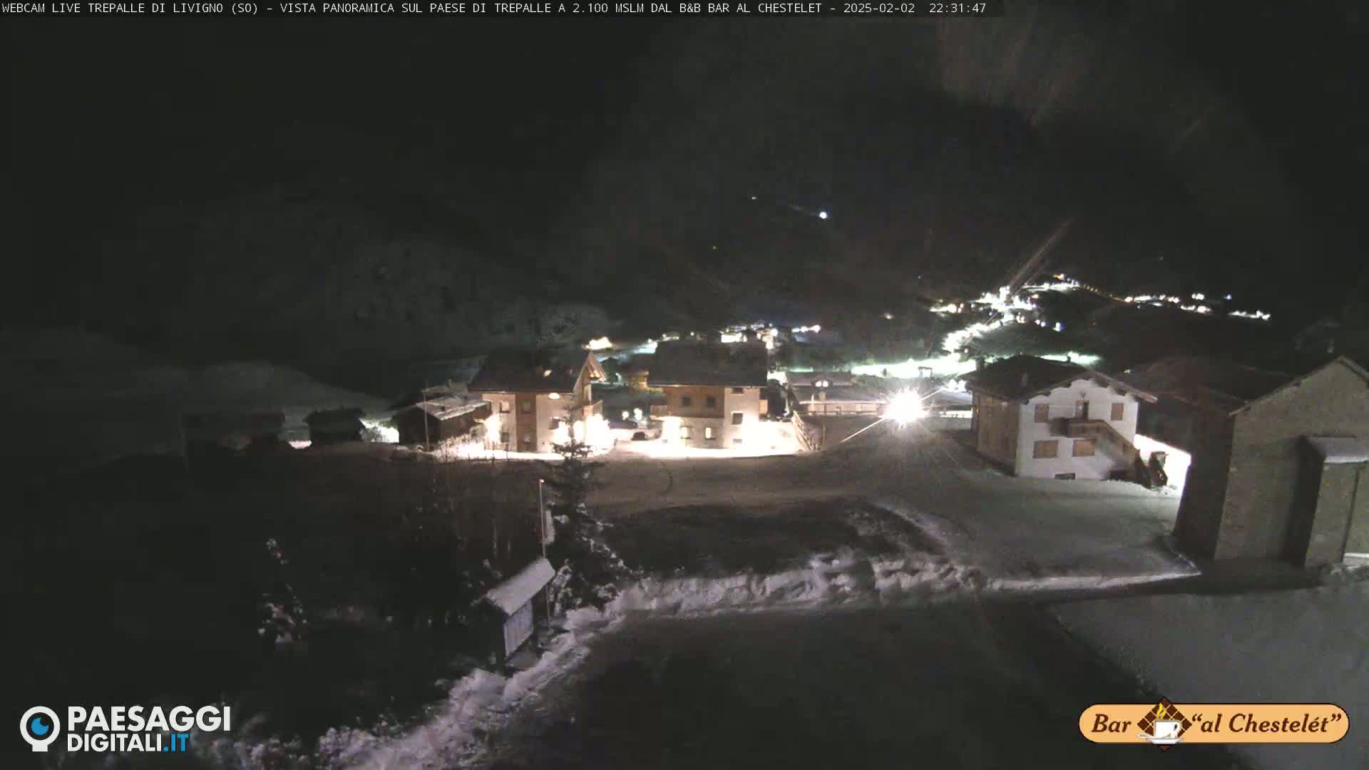 A snow-covered village is illuminated at night.