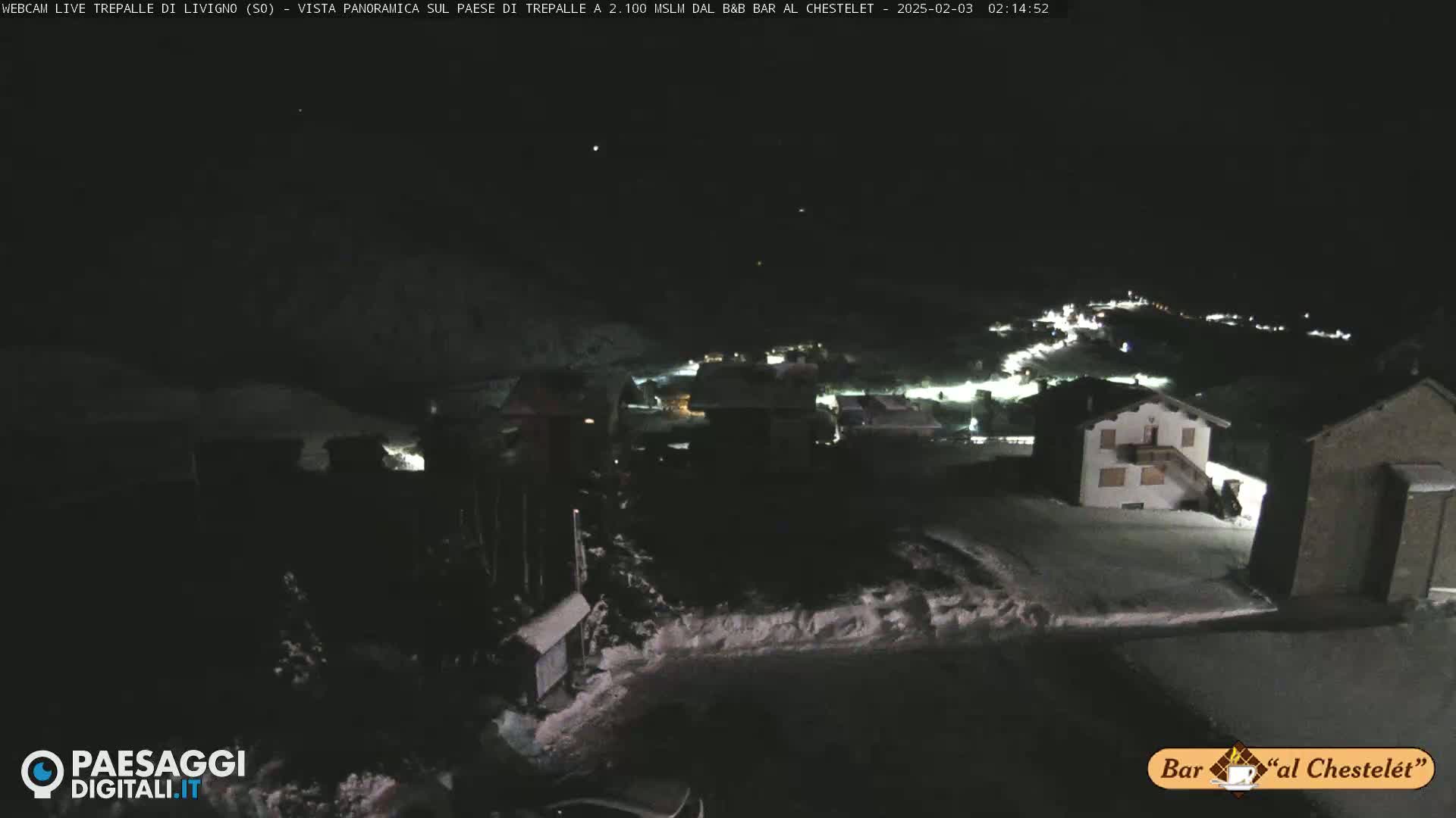 A nighttime, snow-covered village is visible under a dark sky.