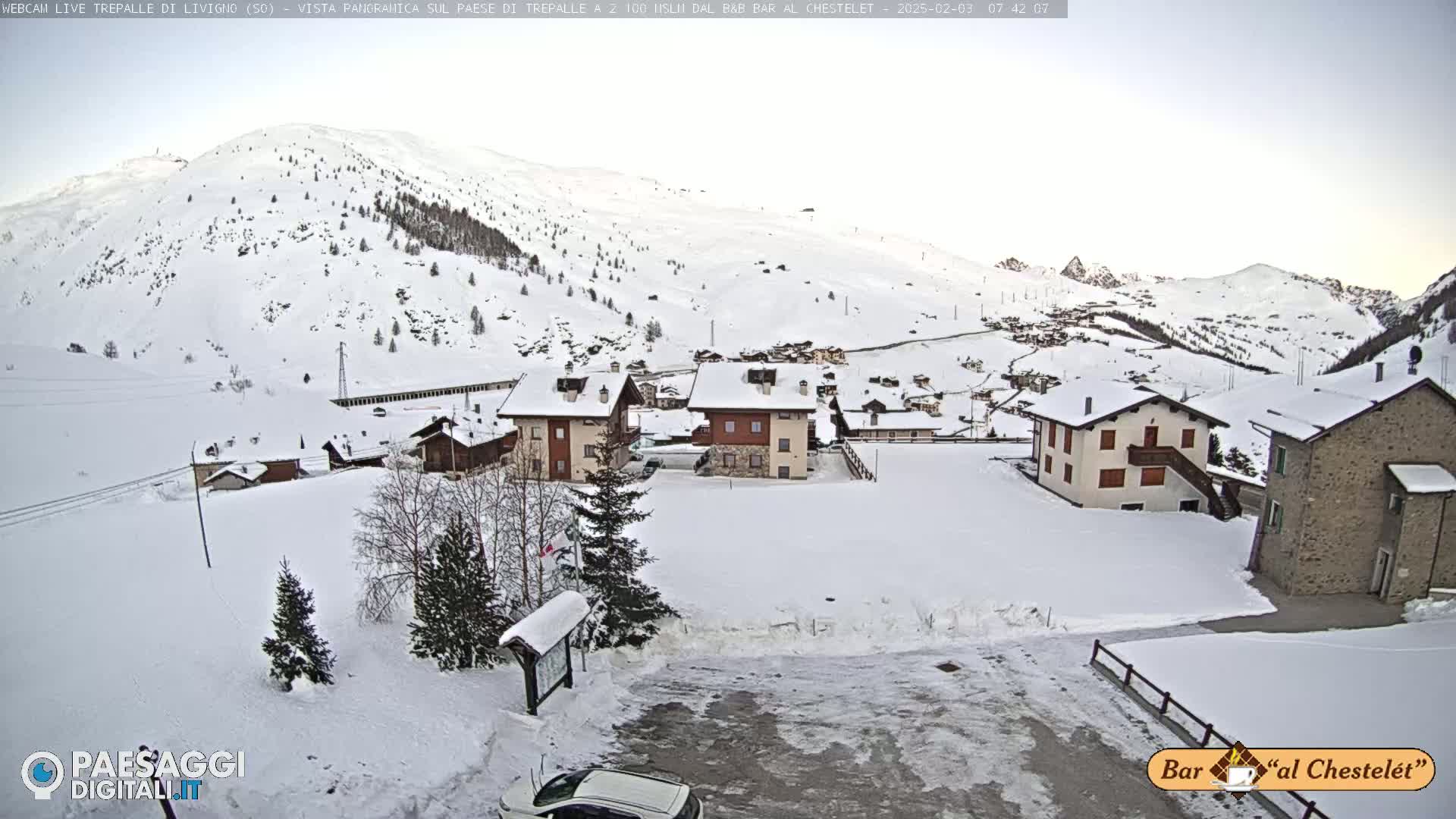 A snow-covered village nestled in a mountainous valley under a pale, overcast sky.