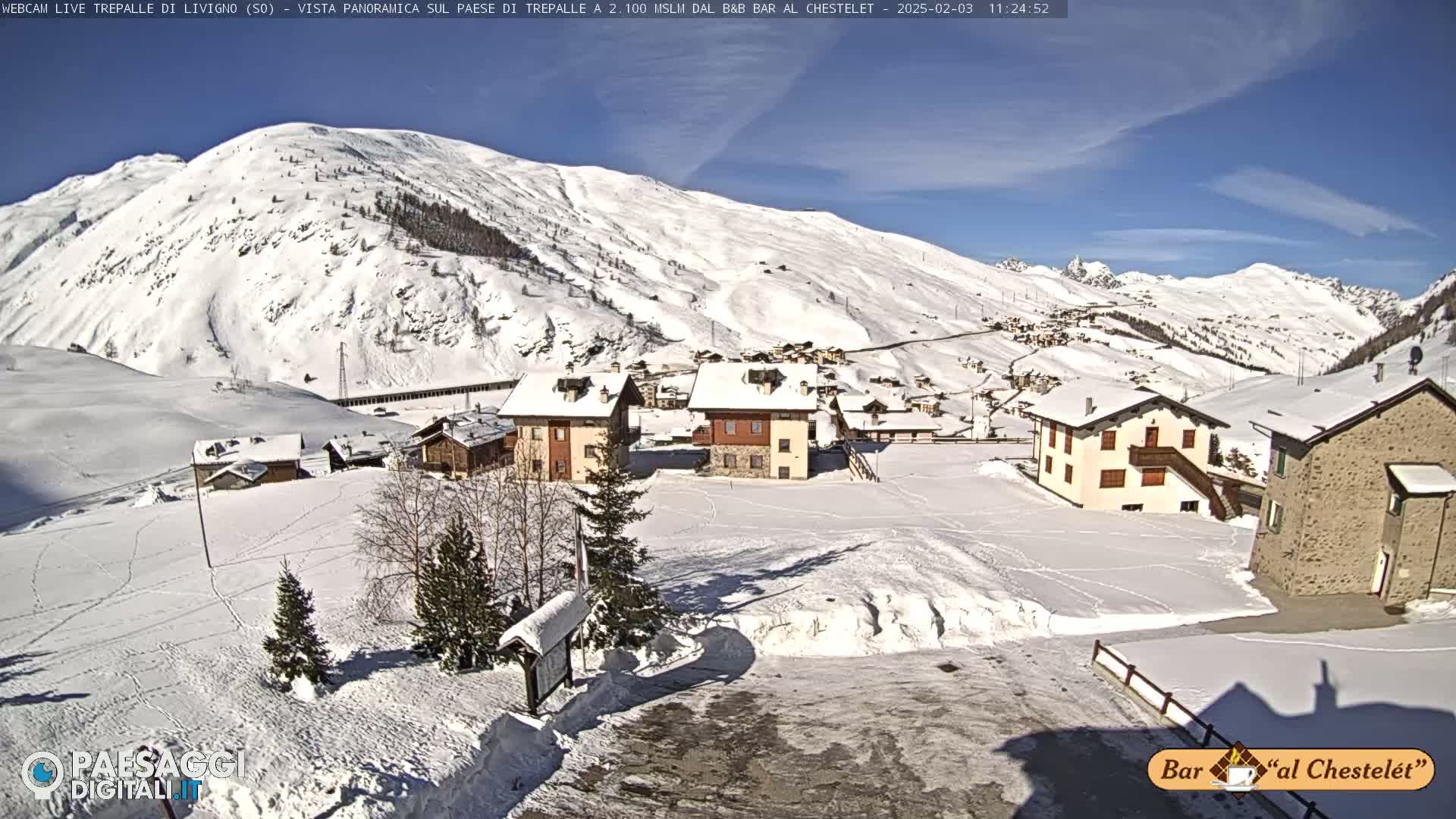 A snow-covered village nestled in a mountainous valley on a sunny day.