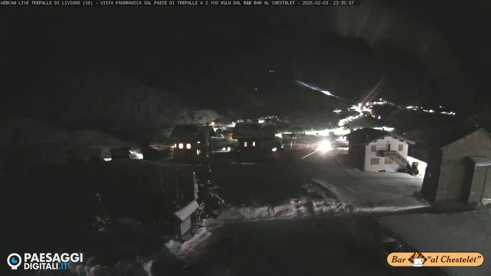 A snow-covered village is illuminated at night.