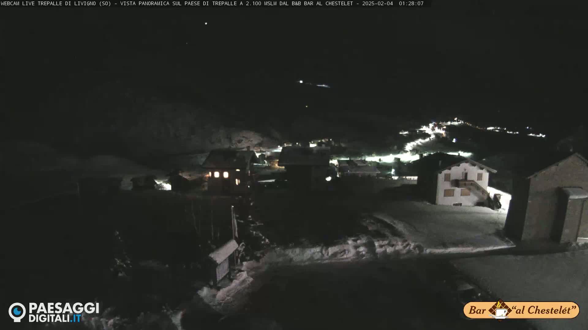 A nighttime, snow-covered village scene under a clear, dark sky.