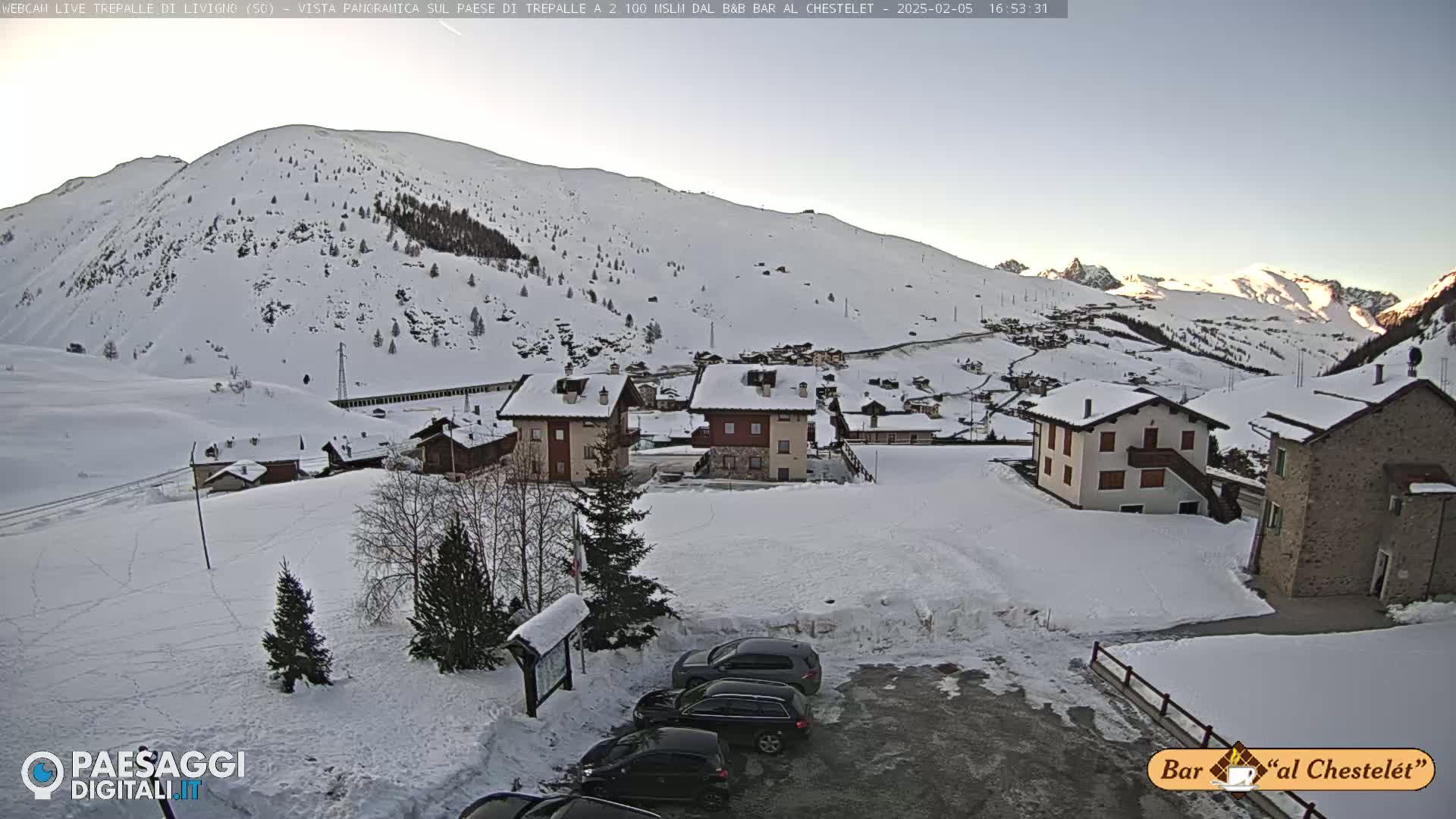 A snow-covered village nestled in a mountain valley under a clear, bright sky.