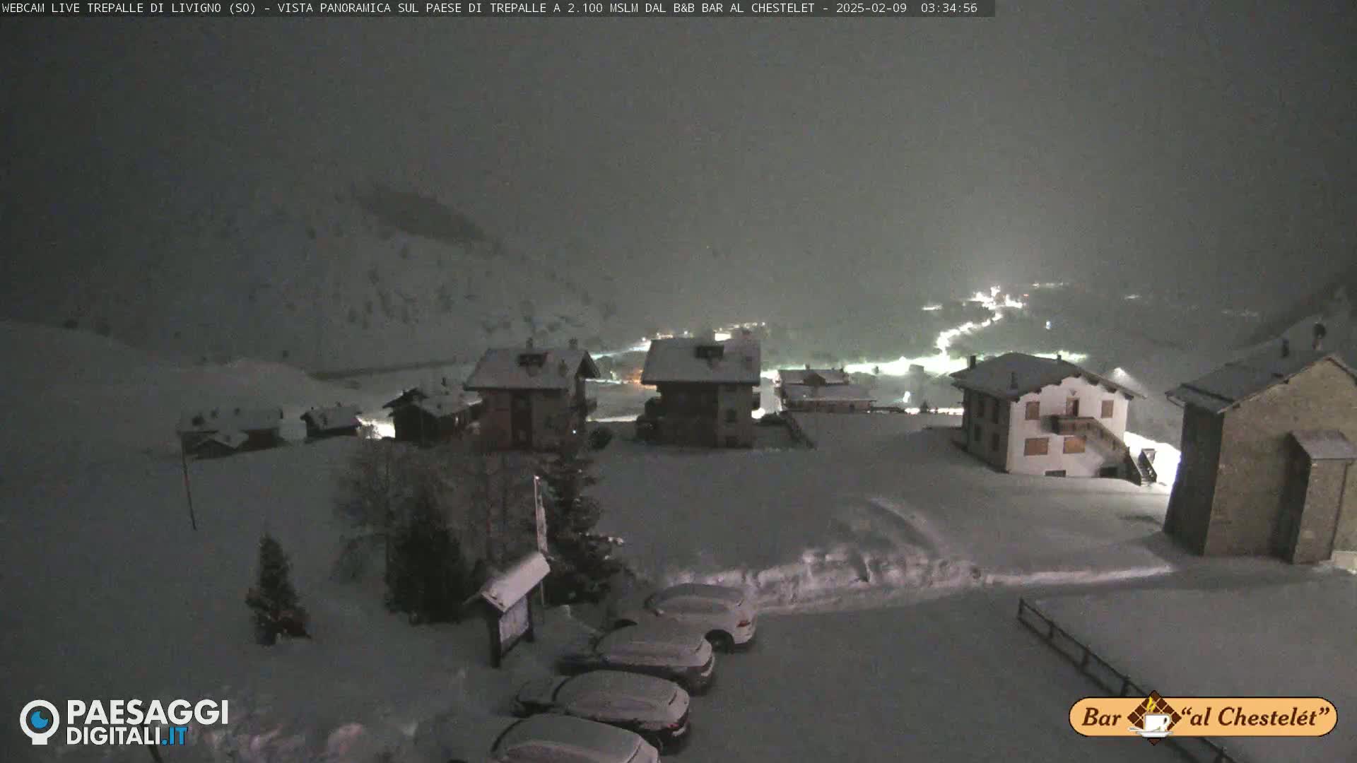 A snow-covered village is seen at night under a heavy snowfall.