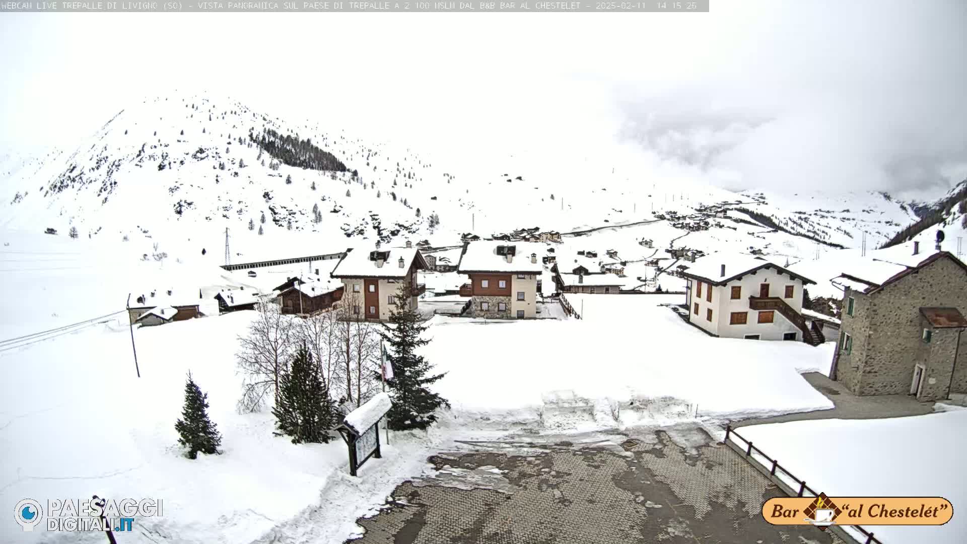 A snow-covered village nestled in a mountainous region under an overcast sky.