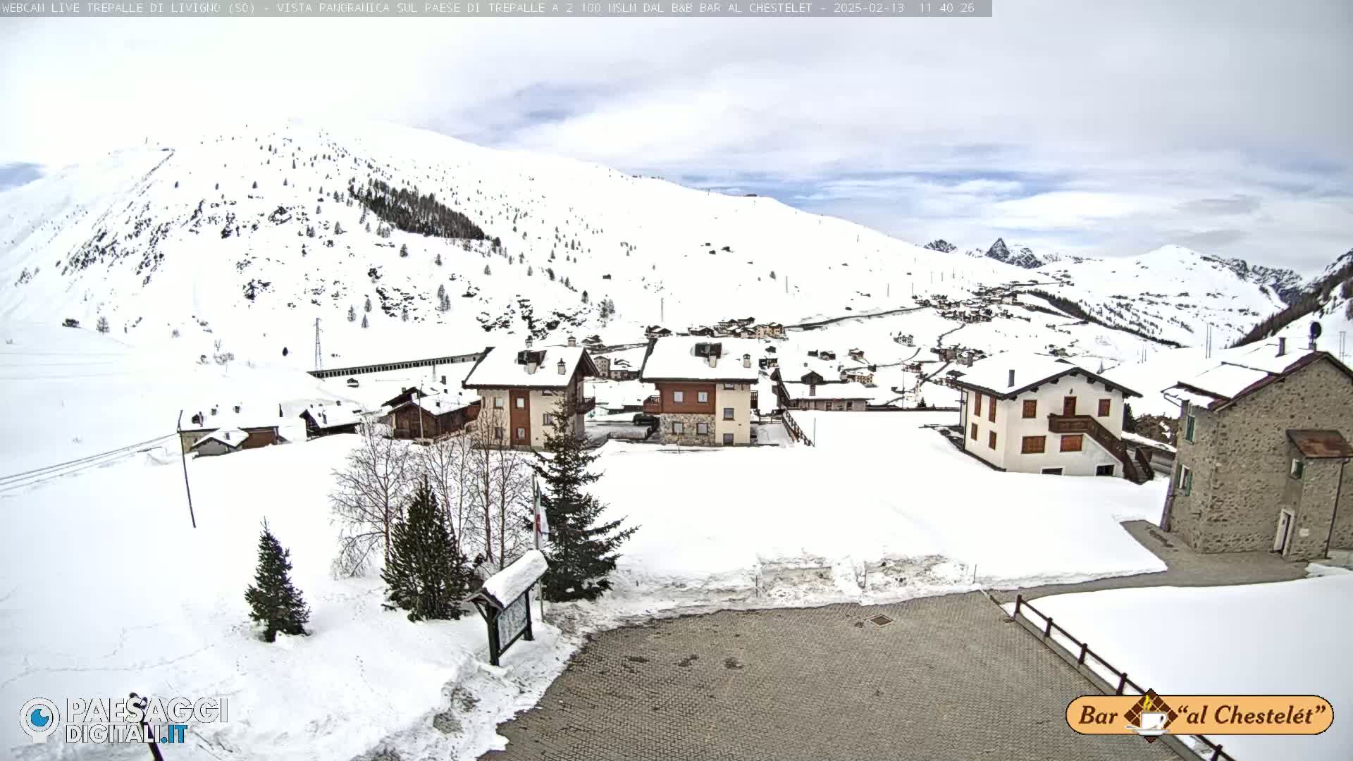 A snow-covered village nestled in a mountainous region under a cloudy sky.