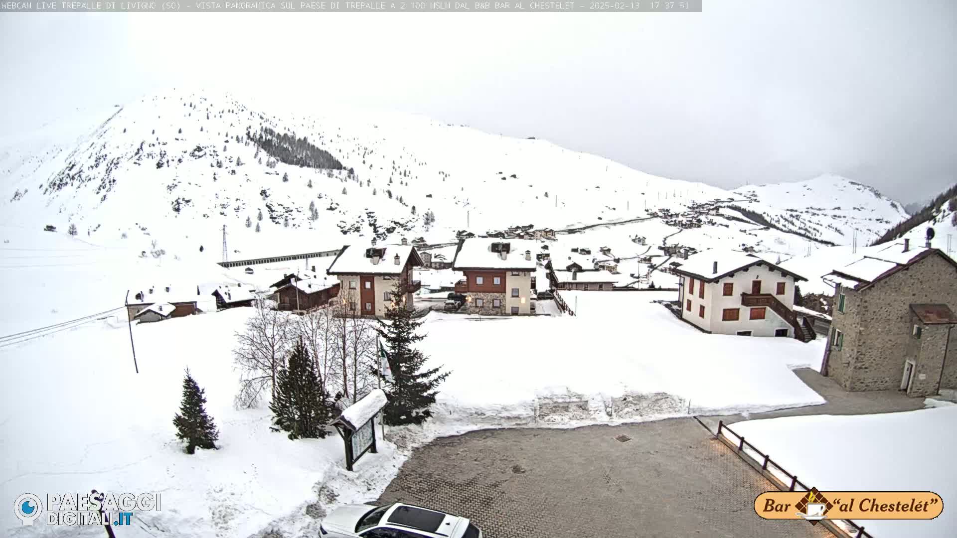 A snow-covered village nestled in a mountainous region under an overcast sky.