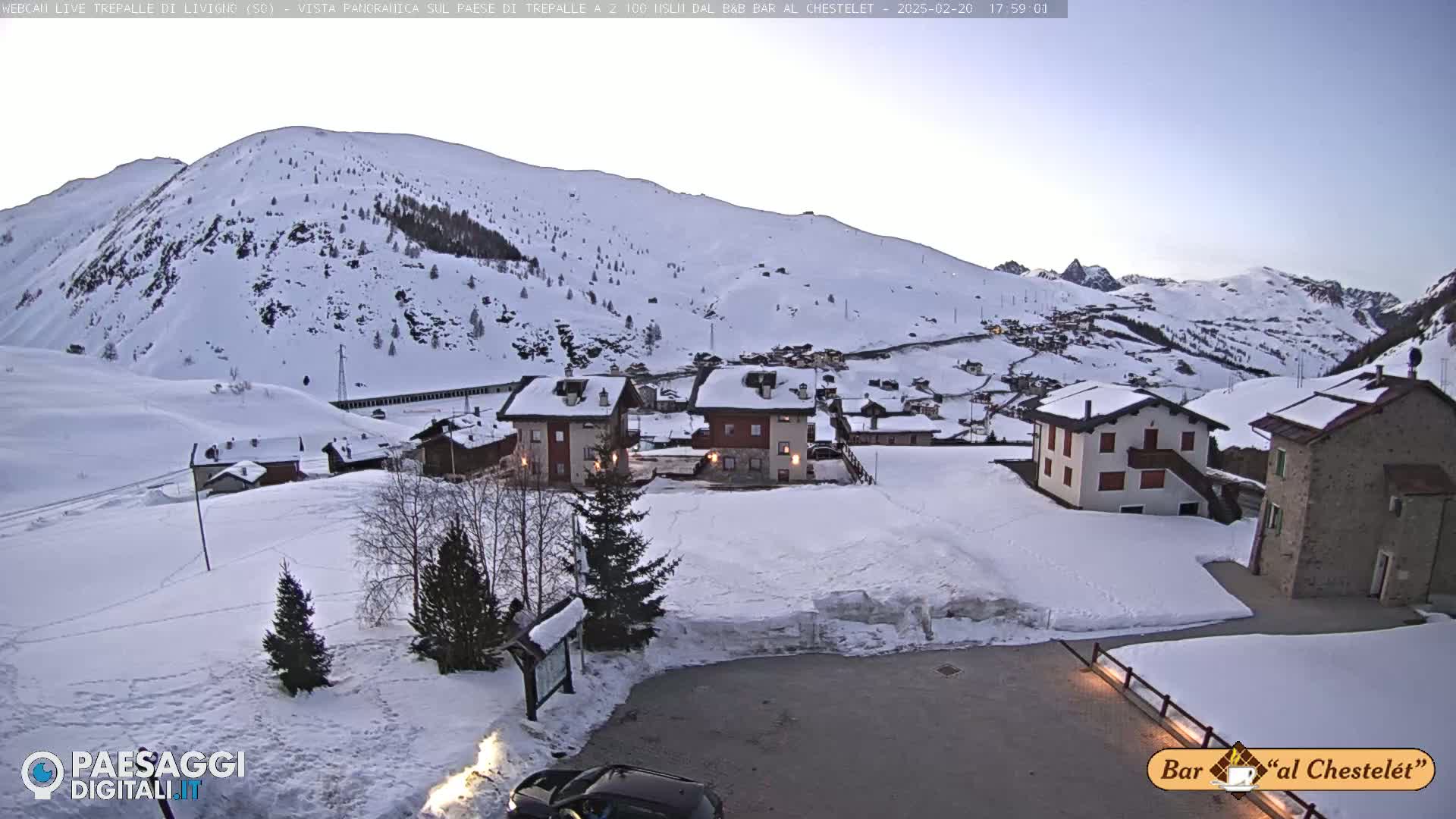A snow-covered village nestled in a mountain valley under a twilight sky.