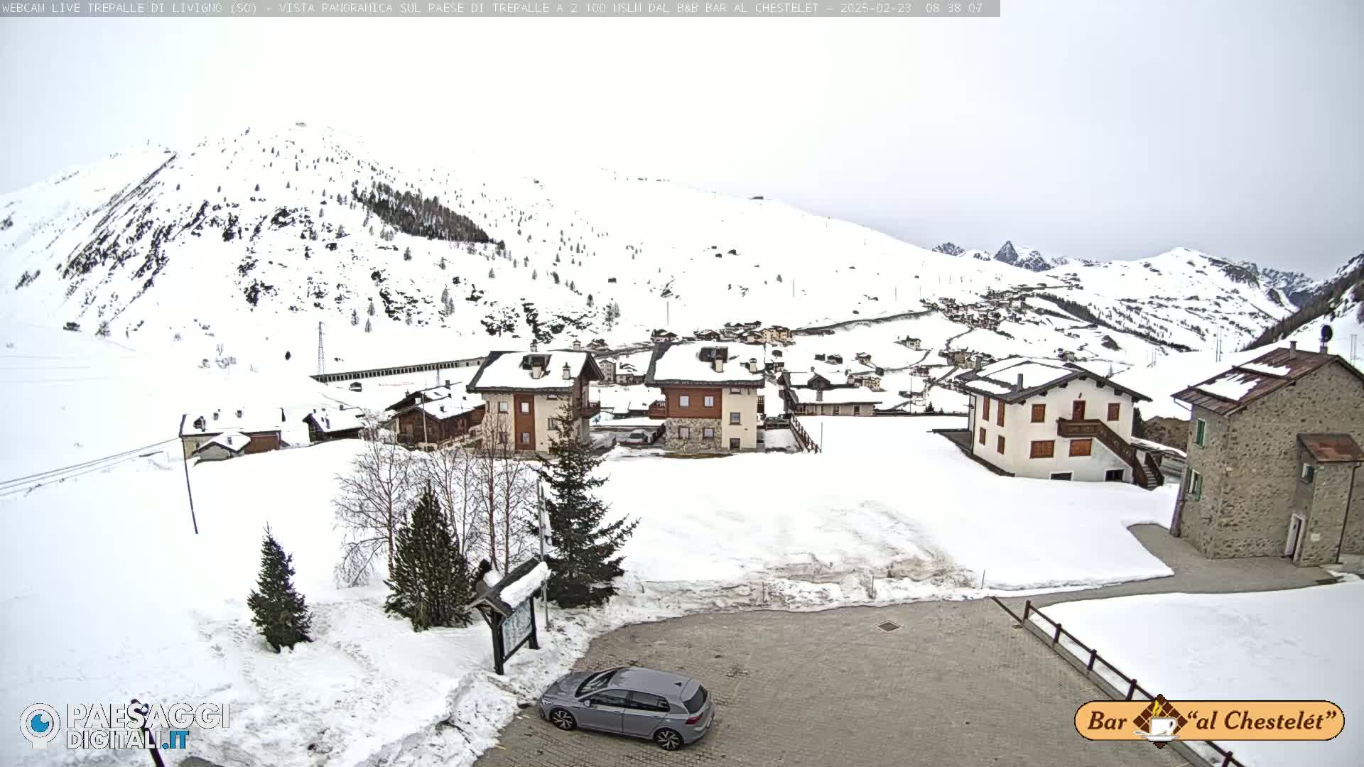 A snow-covered village nestled in a mountainous region under an overcast sky.