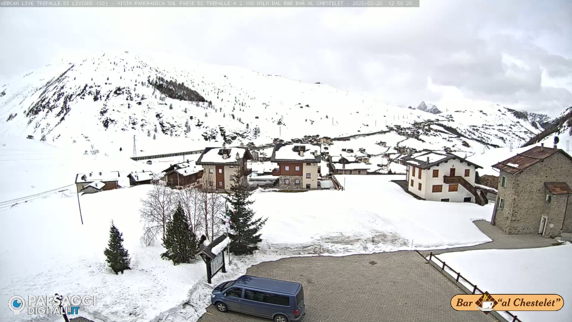 A snow-covered village nestled in a mountainous region under a cloudy sky.