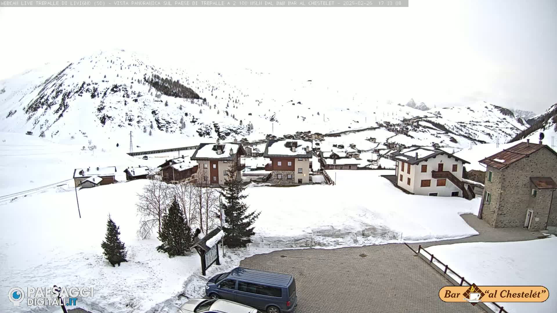A snow-covered village nestled in a mountainous region under an overcast sky.
