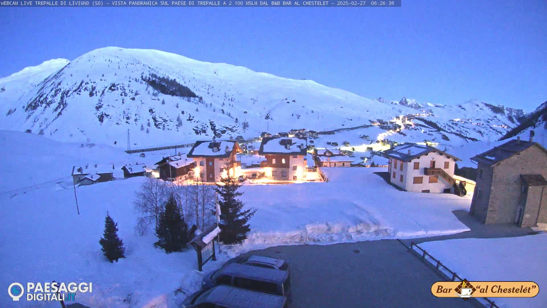 A snow-covered village nestled in a valley between mountains at twilight.