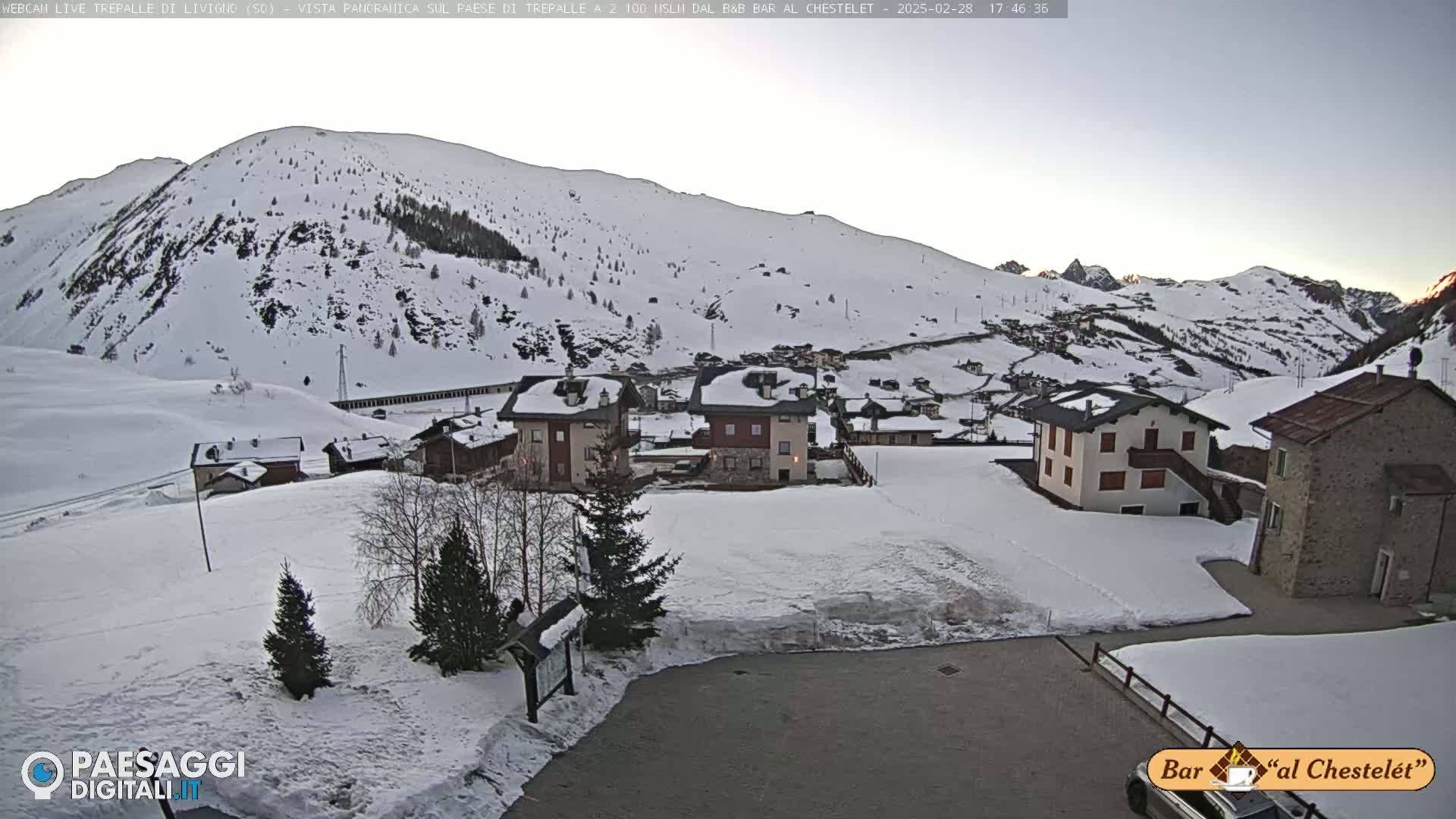 A snow-covered village nestled in a mountainous region under a twilight sky.