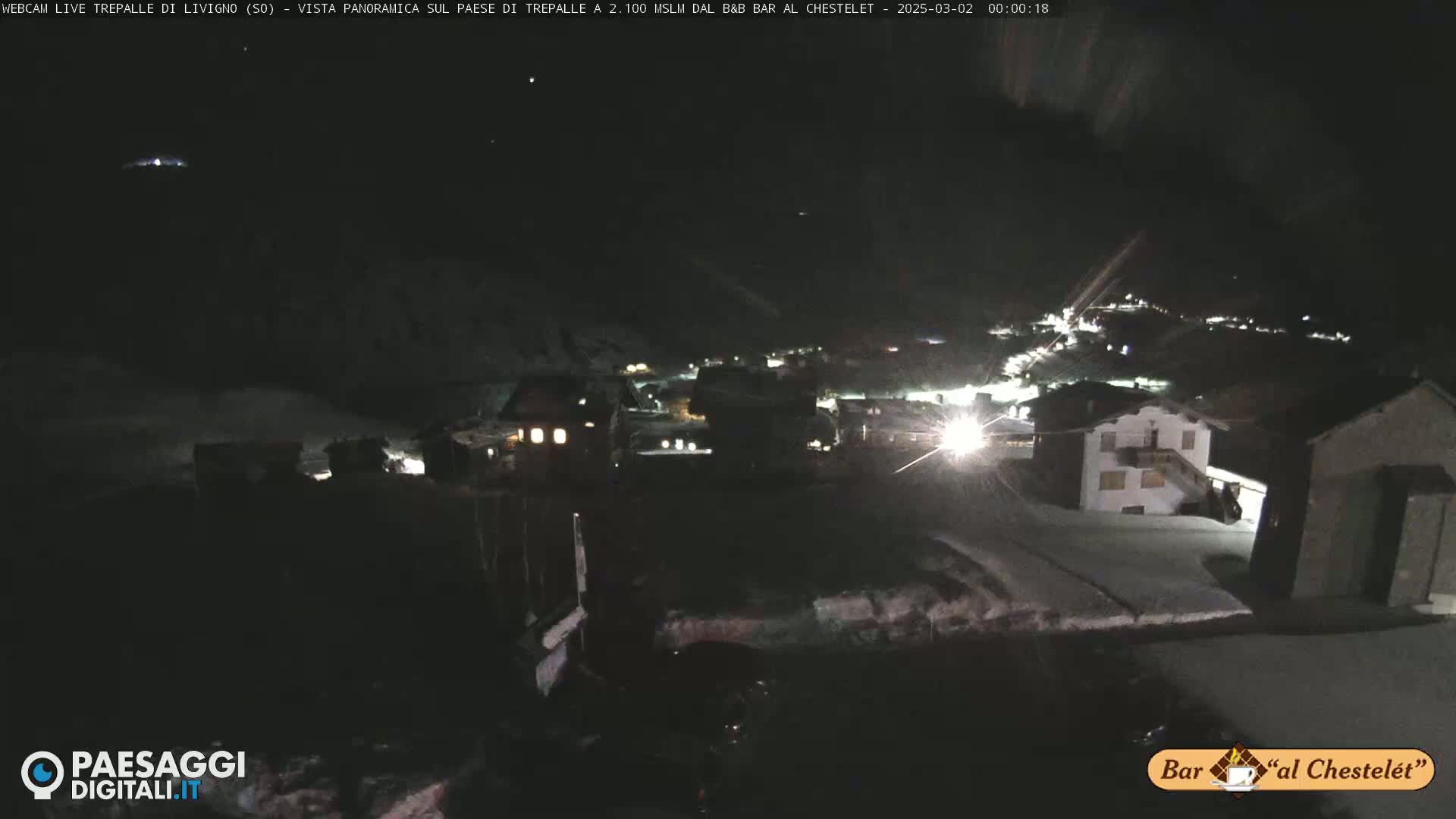 A snow-covered village is illuminated at night.