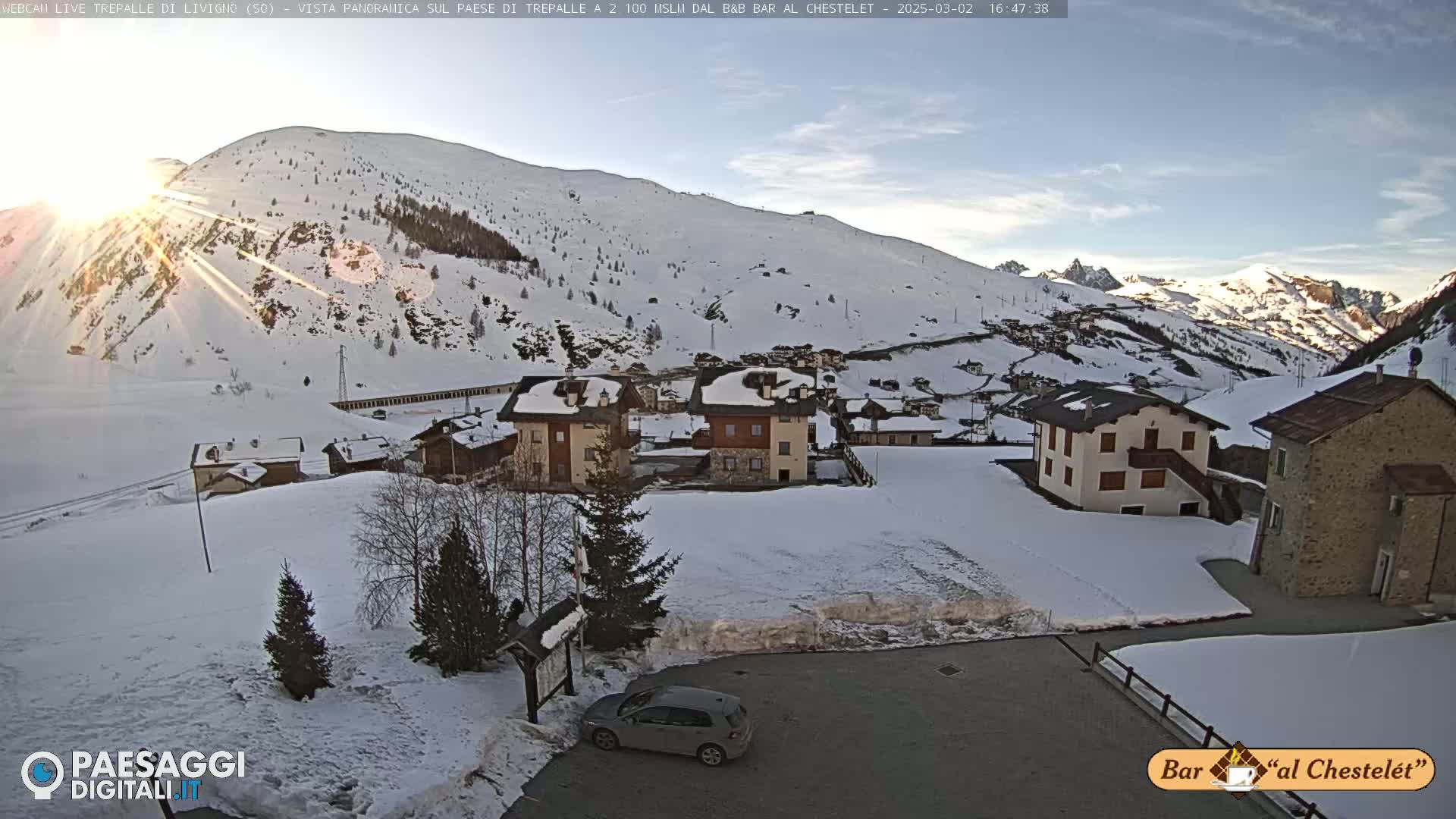 A snow-covered village nestled in a mountain valley, bathed in the sun's rays.