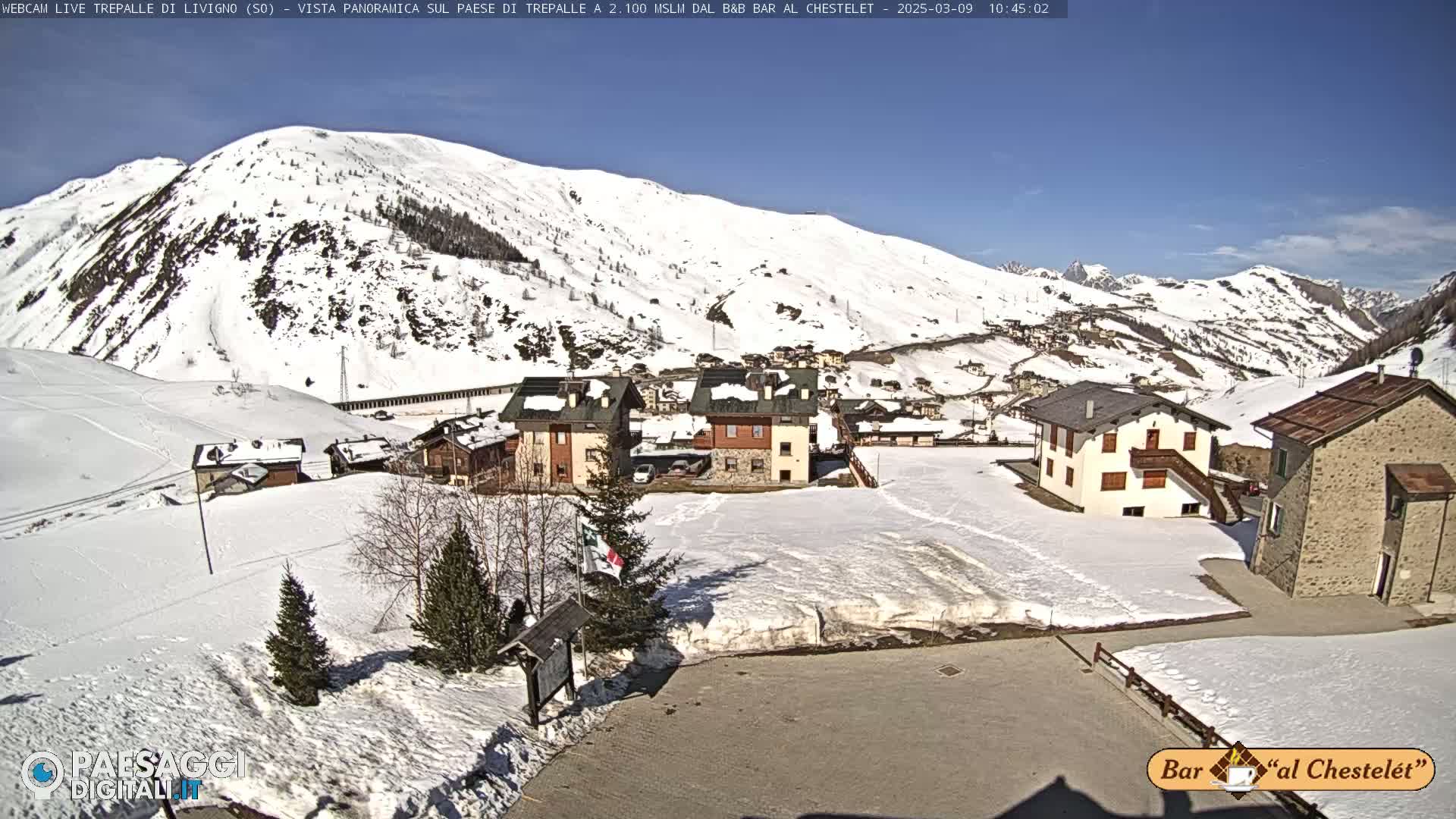 A snow-covered mountain village nestled in a valley under a clear blue sky.