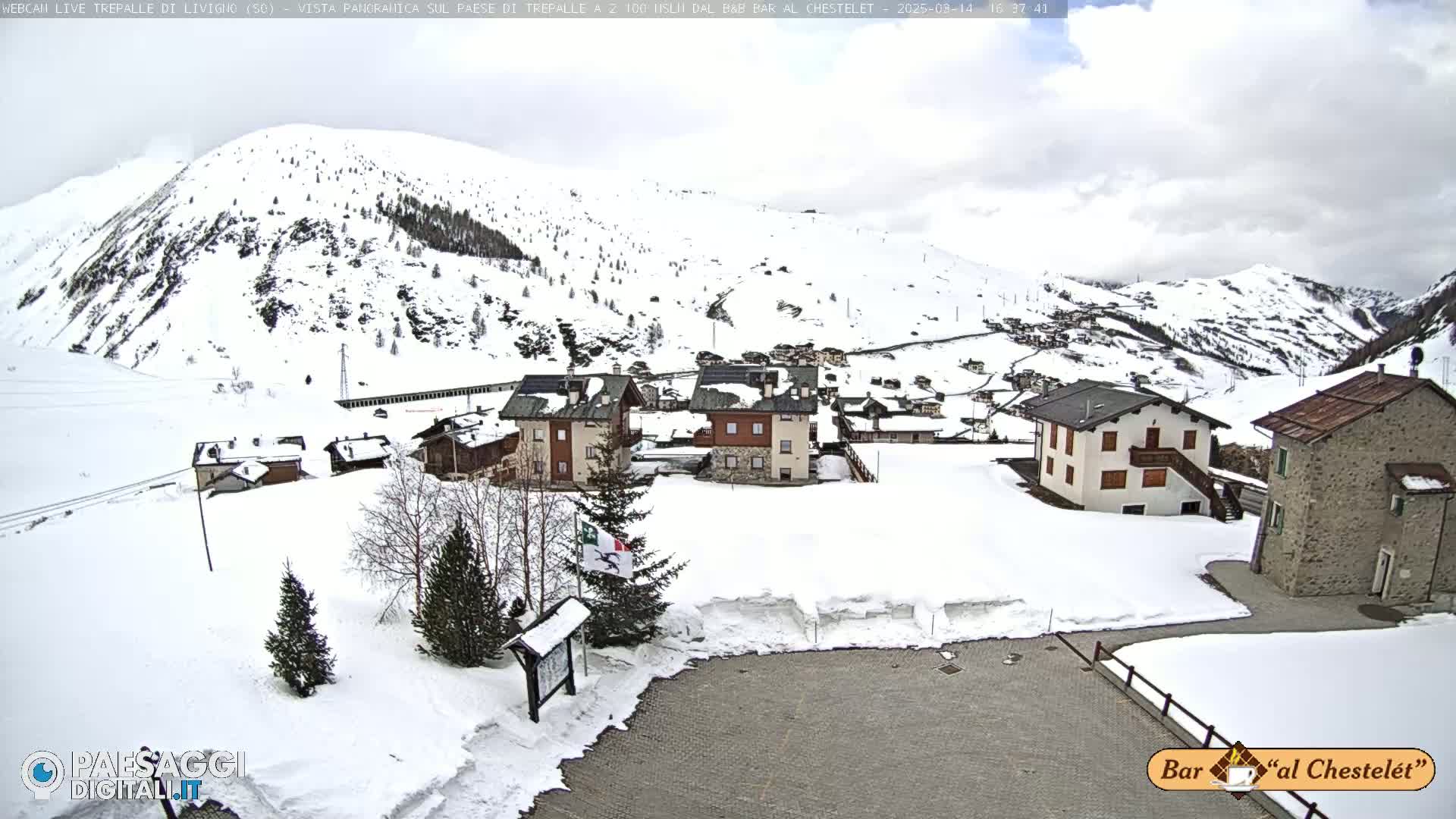 A snow-covered village nestled in a mountainous region under a cloudy sky.