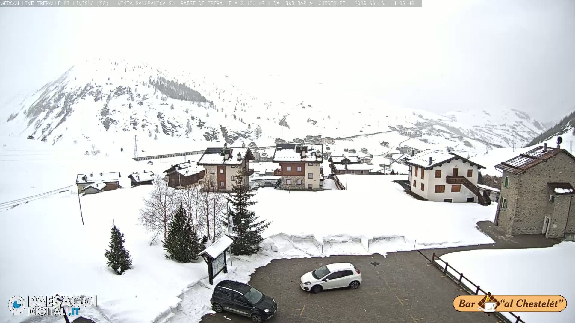 A snow-covered village nestled in a mountainous valley during an overcast day.