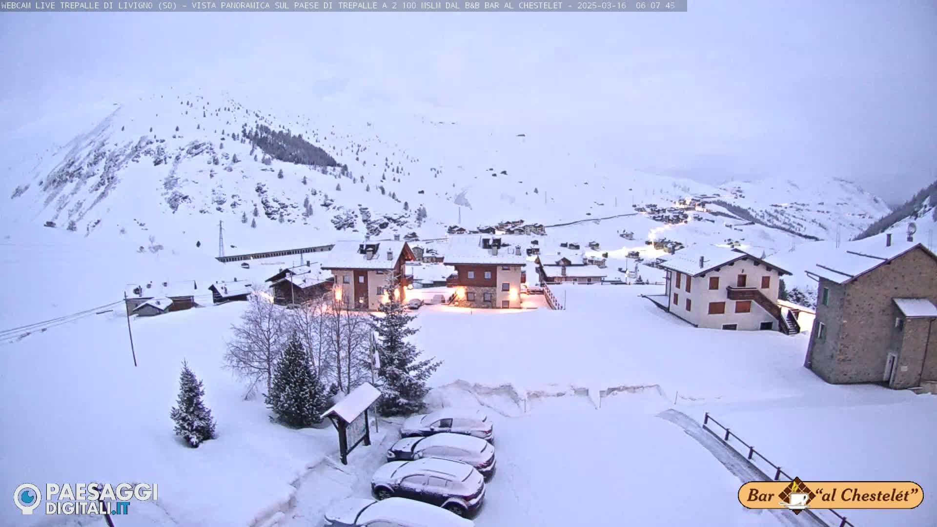 A snow-covered village nestled in a mountainous region under a cloudy, dim sky.