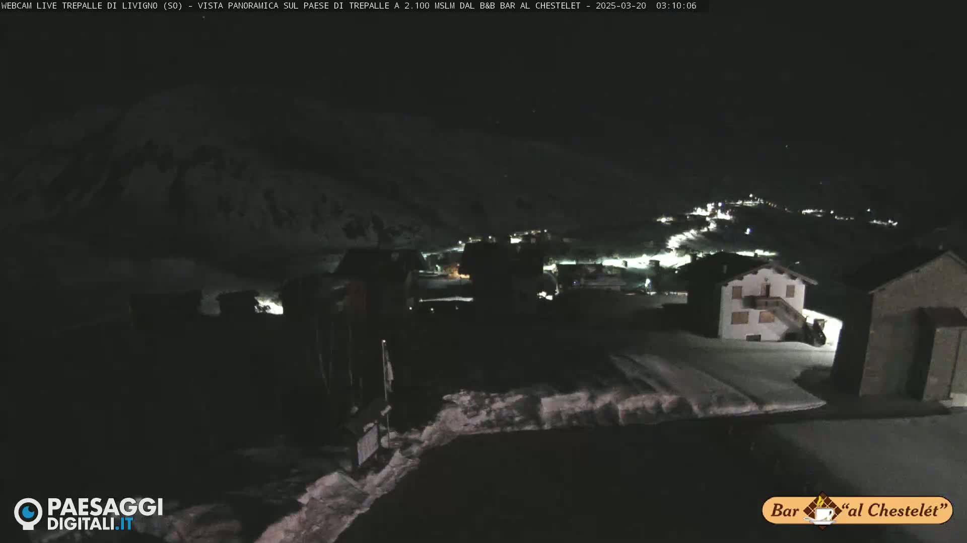 A nighttime, snow-covered village is visible under a dark sky.