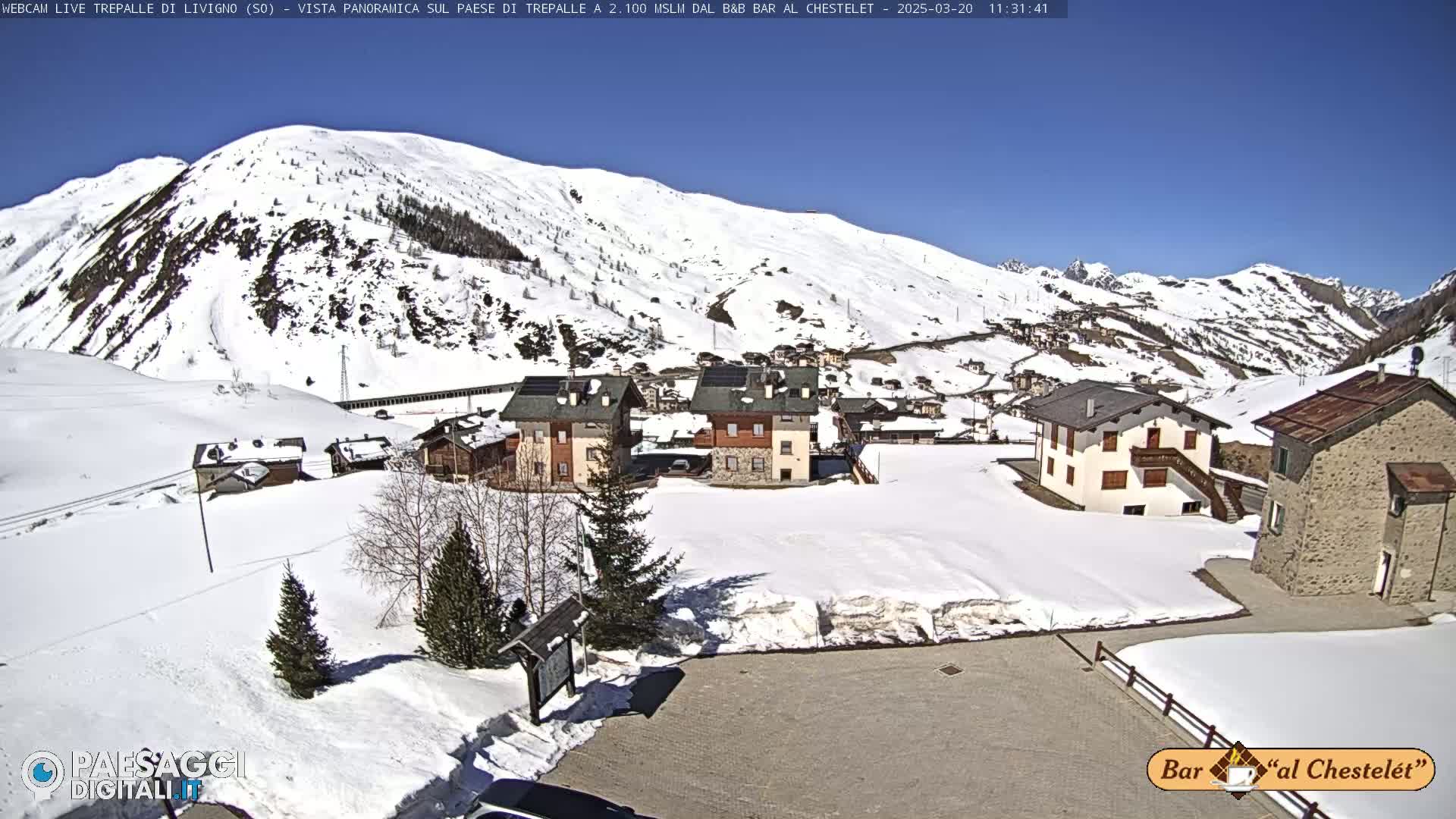 A snow-covered village nestled in a mountain valley on a sunny day.