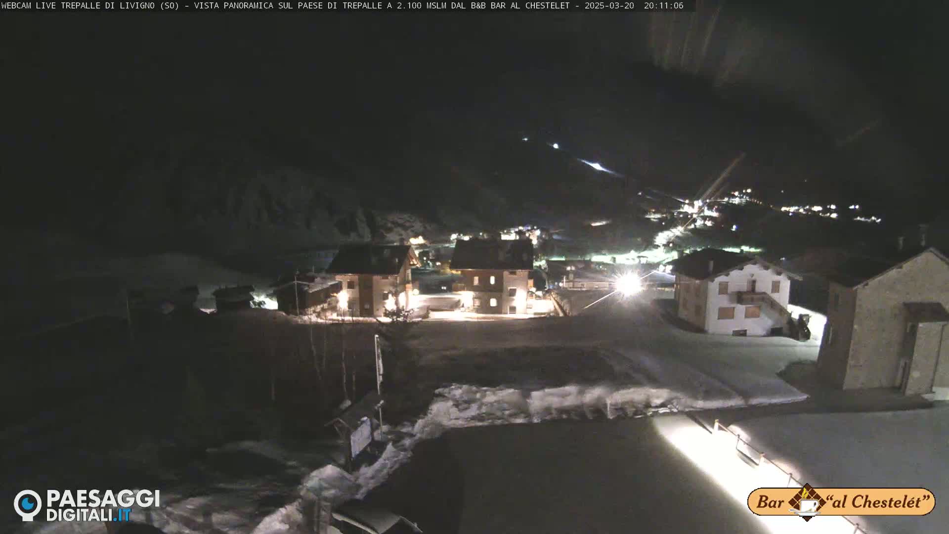 A nighttime, snowy view of a small village nestled in a mountain valley.