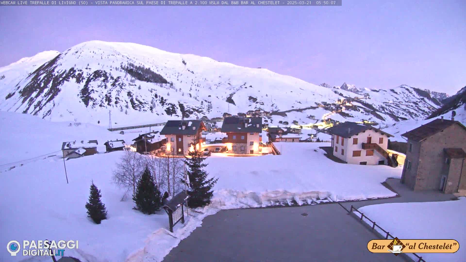 A snow-covered village nestled in a mountain valley at twilight.