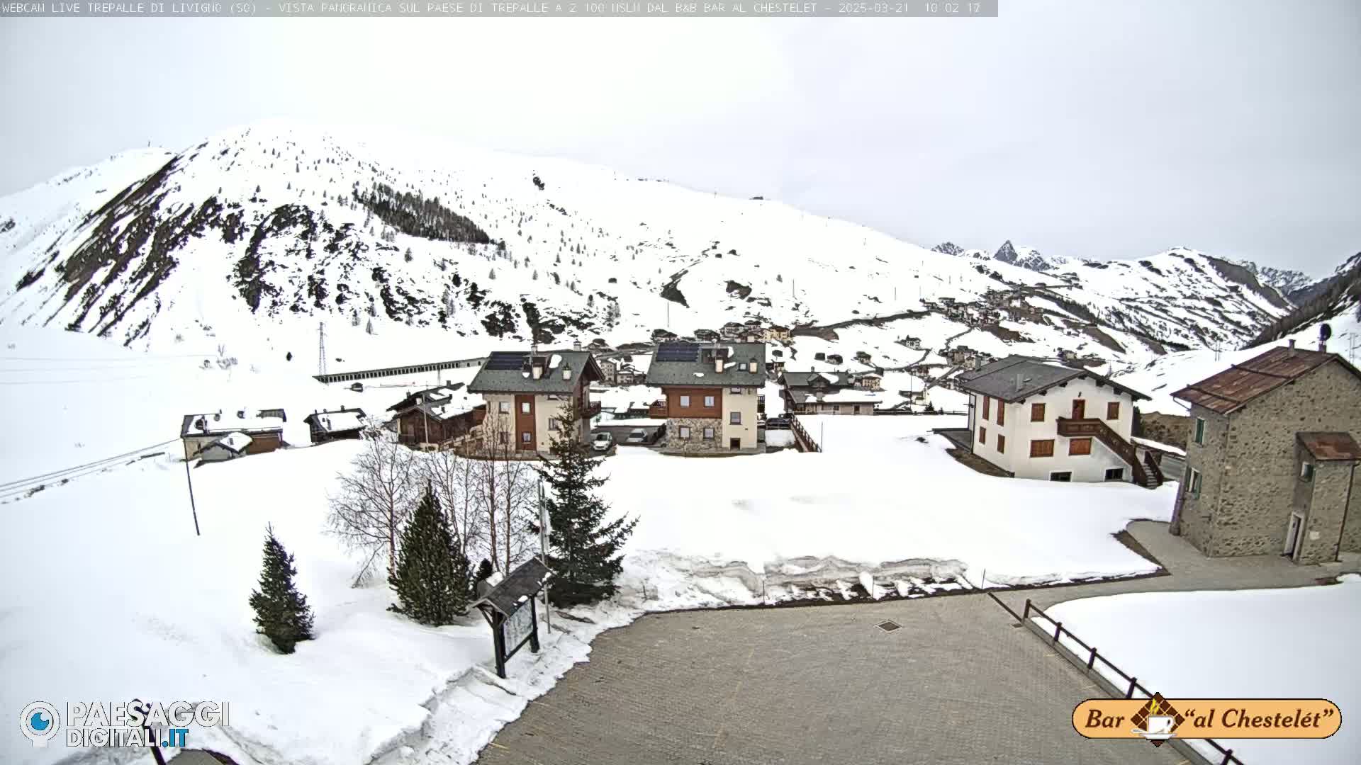 A snow-covered village nestled in a mountainous valley under an overcast sky.