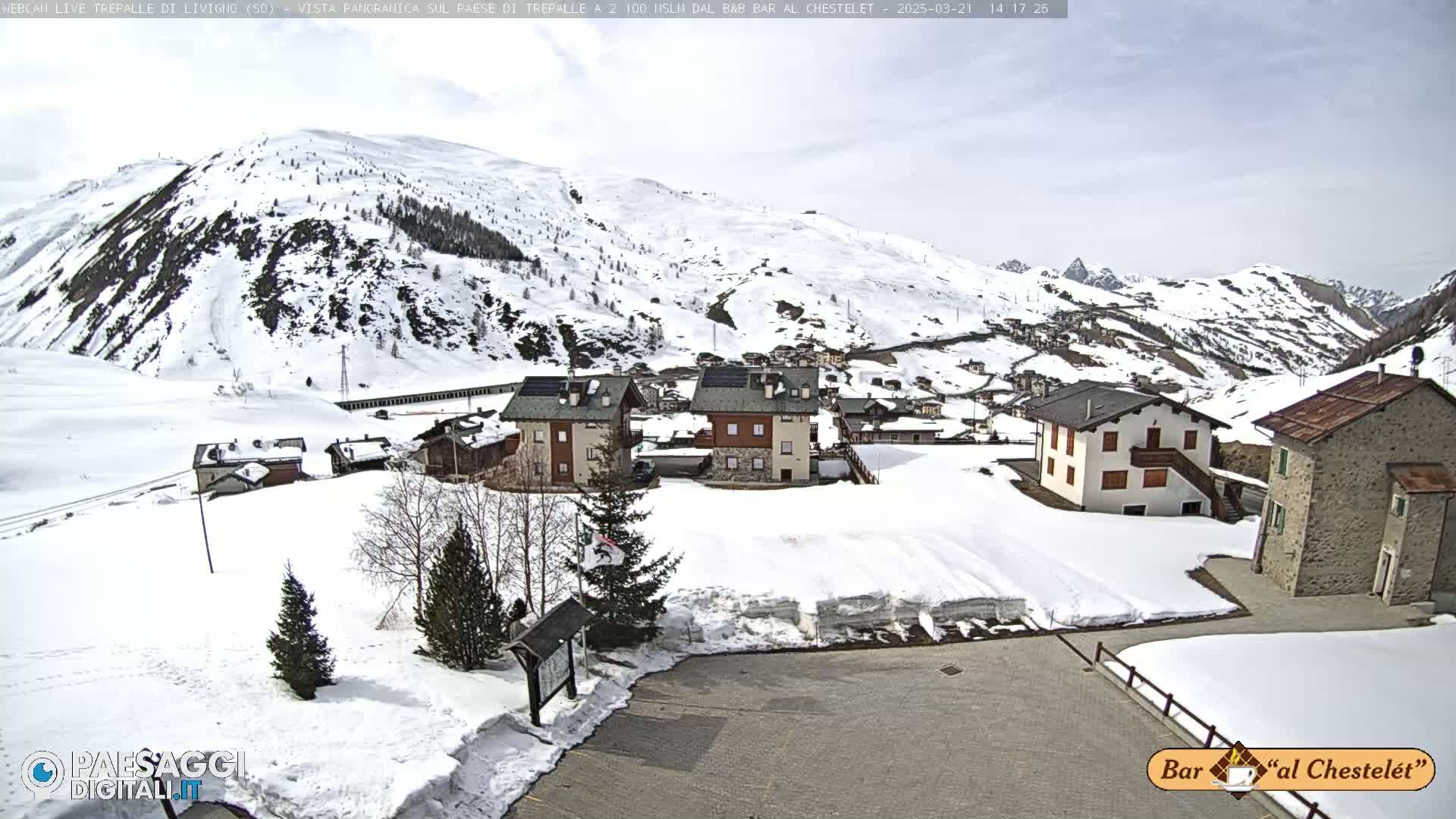 A snow-covered village nestled in a mountainous valley under a mostly clear sky.