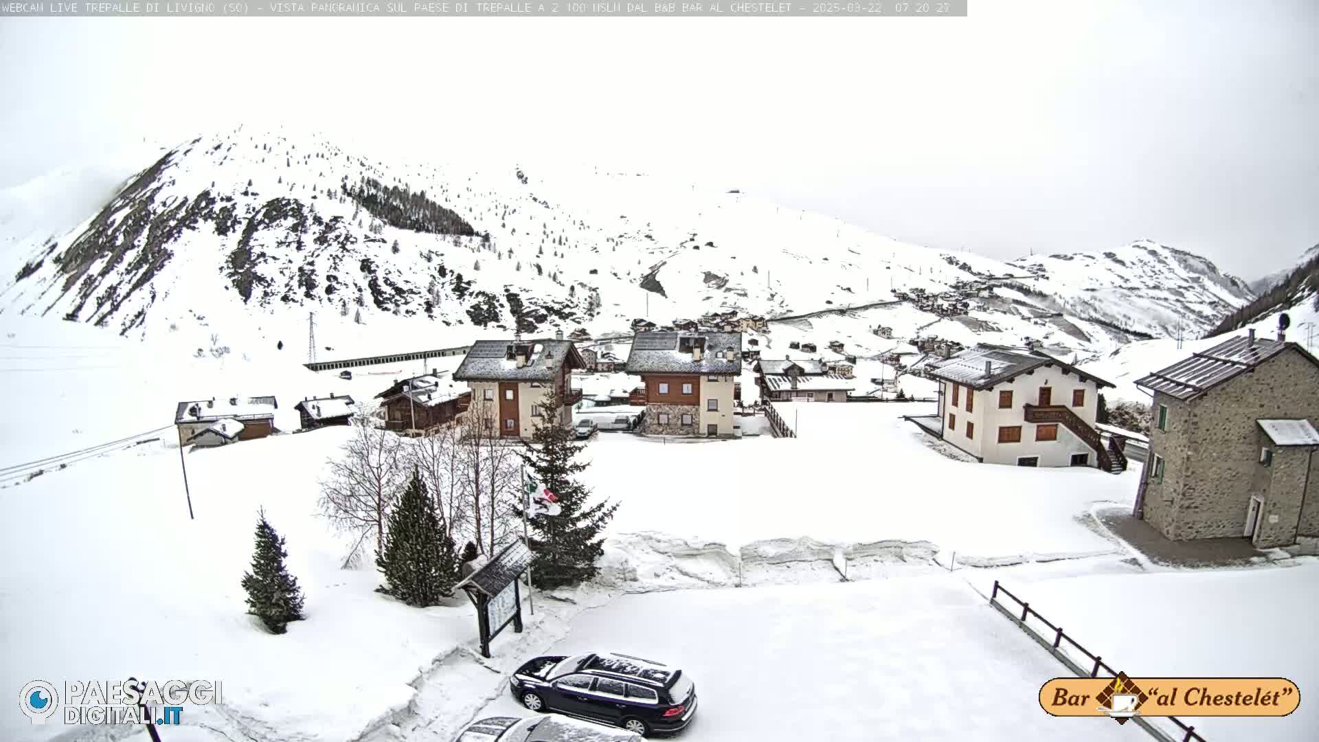 A snow-covered village nestled in a mountainous region under an overcast sky.