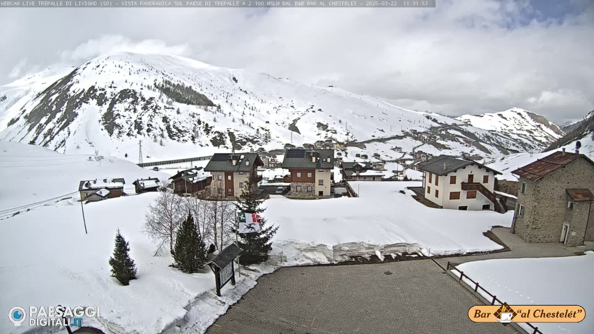 A snow-covered village nestled in a mountain valley under a cloudy sky.