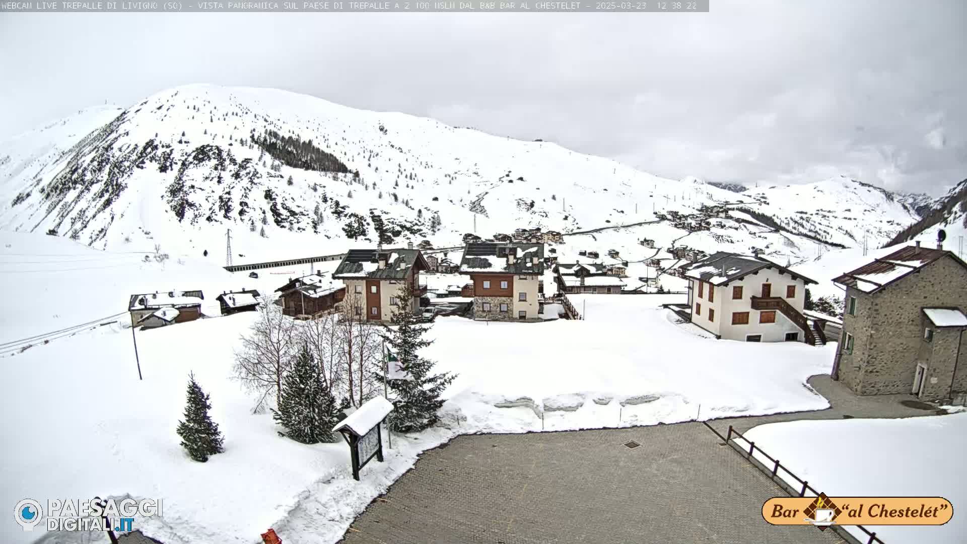 A snow-covered village nestled in a mountainous region under an overcast sky.
