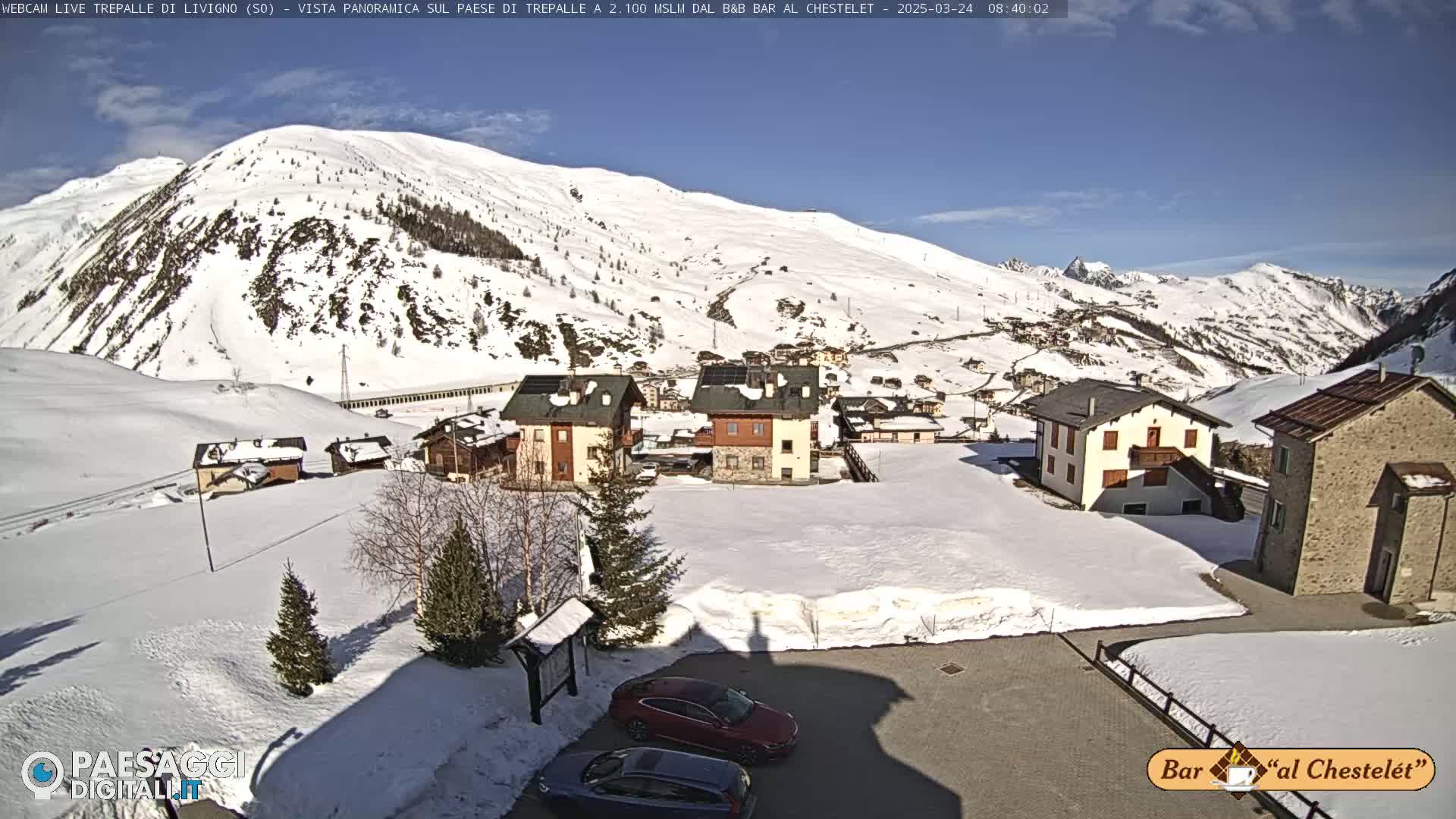 A snow-covered village nestled in a mountainous valley on a sunny day.