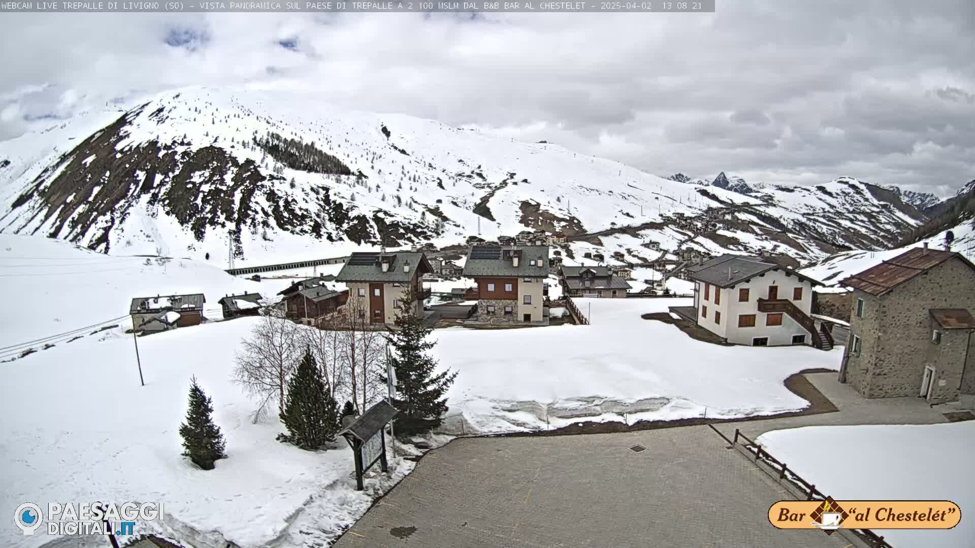 A snow-covered village nestled in a mountain valley under a cloudy sky.