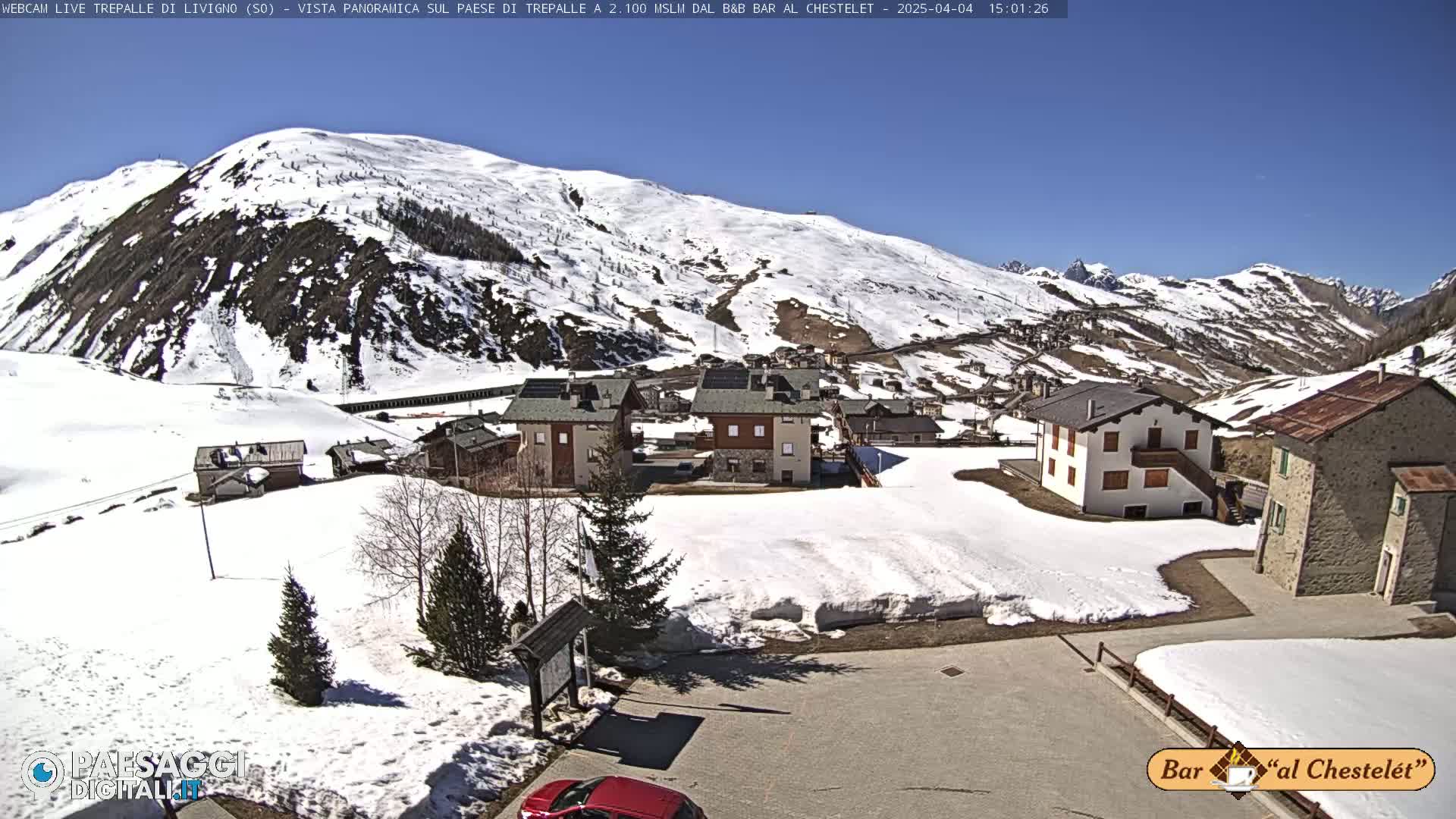 A snow-covered village nestled in a mountain valley under a clear blue sky.