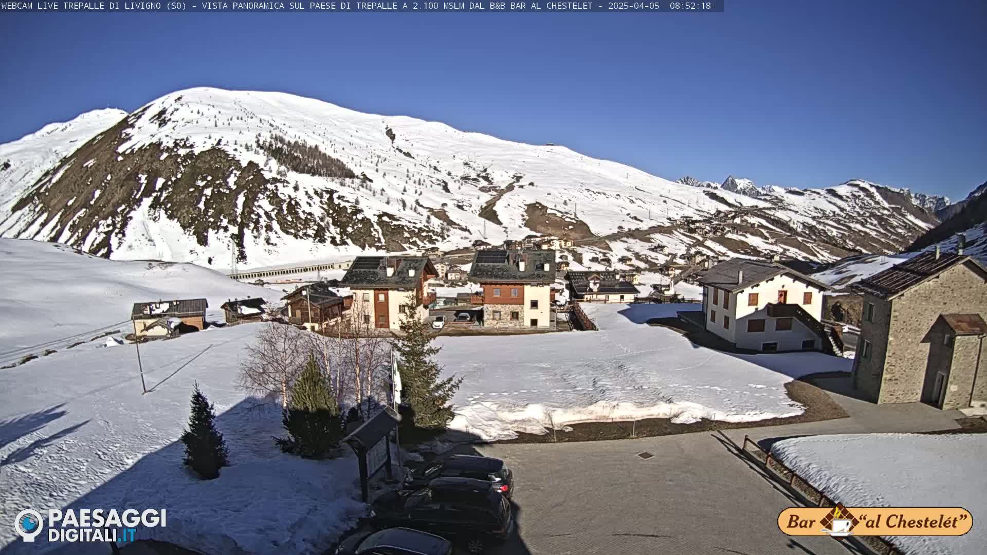 A snow-covered village nestled in a mountain valley on a sunny day.