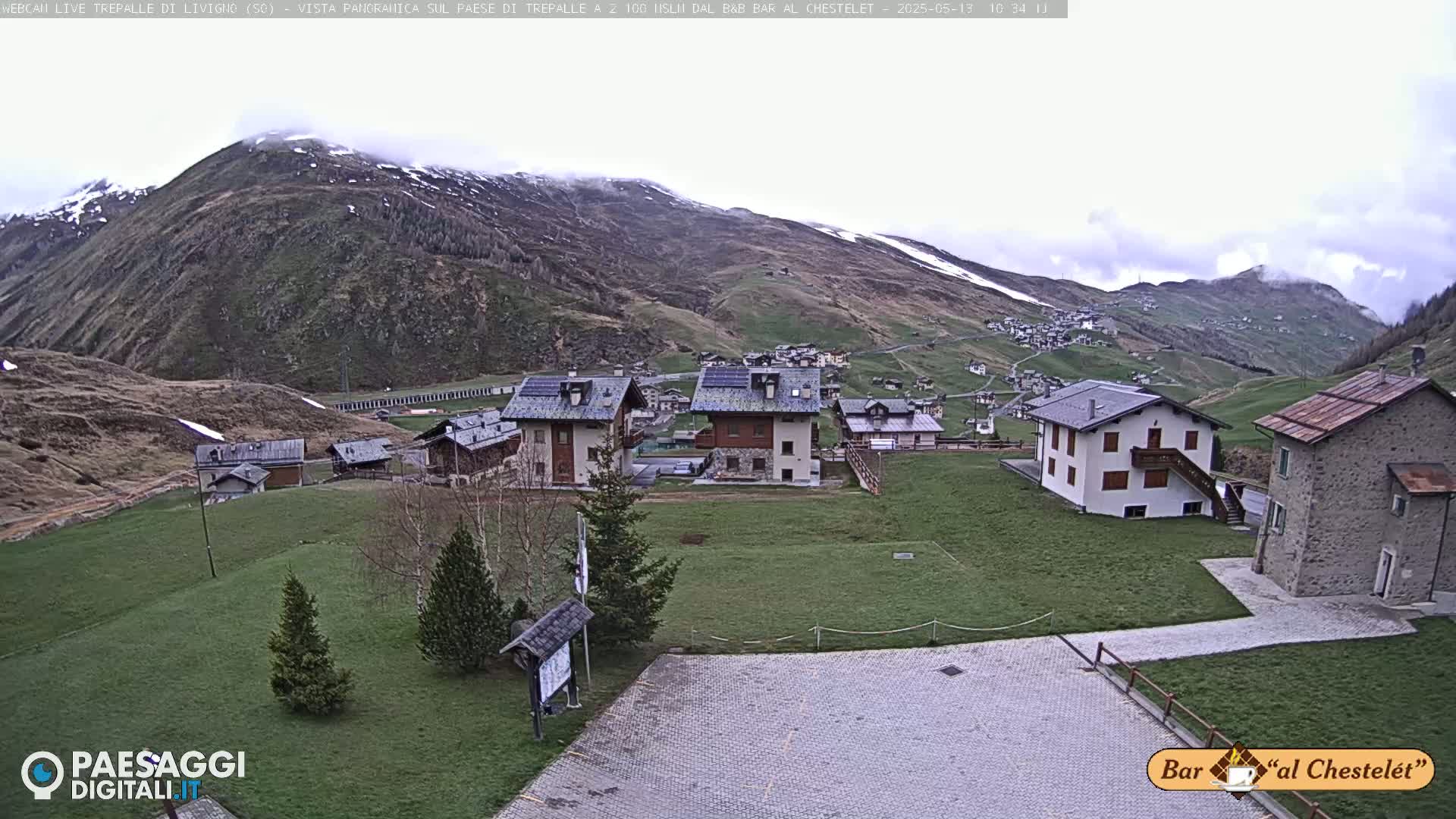 A small village nestled in a valley between mountains under an overcast sky.