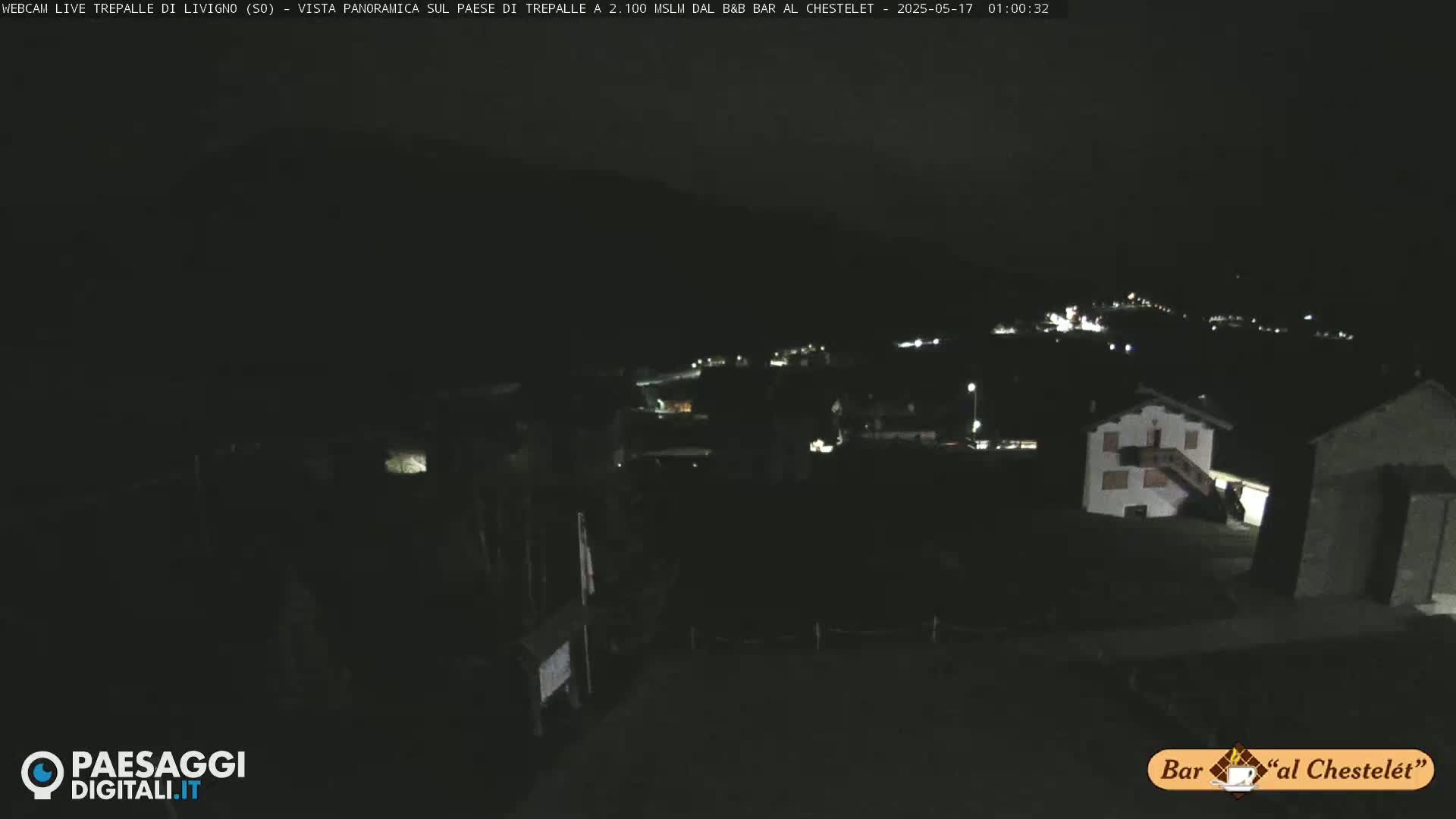 A nighttime long shot of a small town nestled in a dark, mountainous area.
