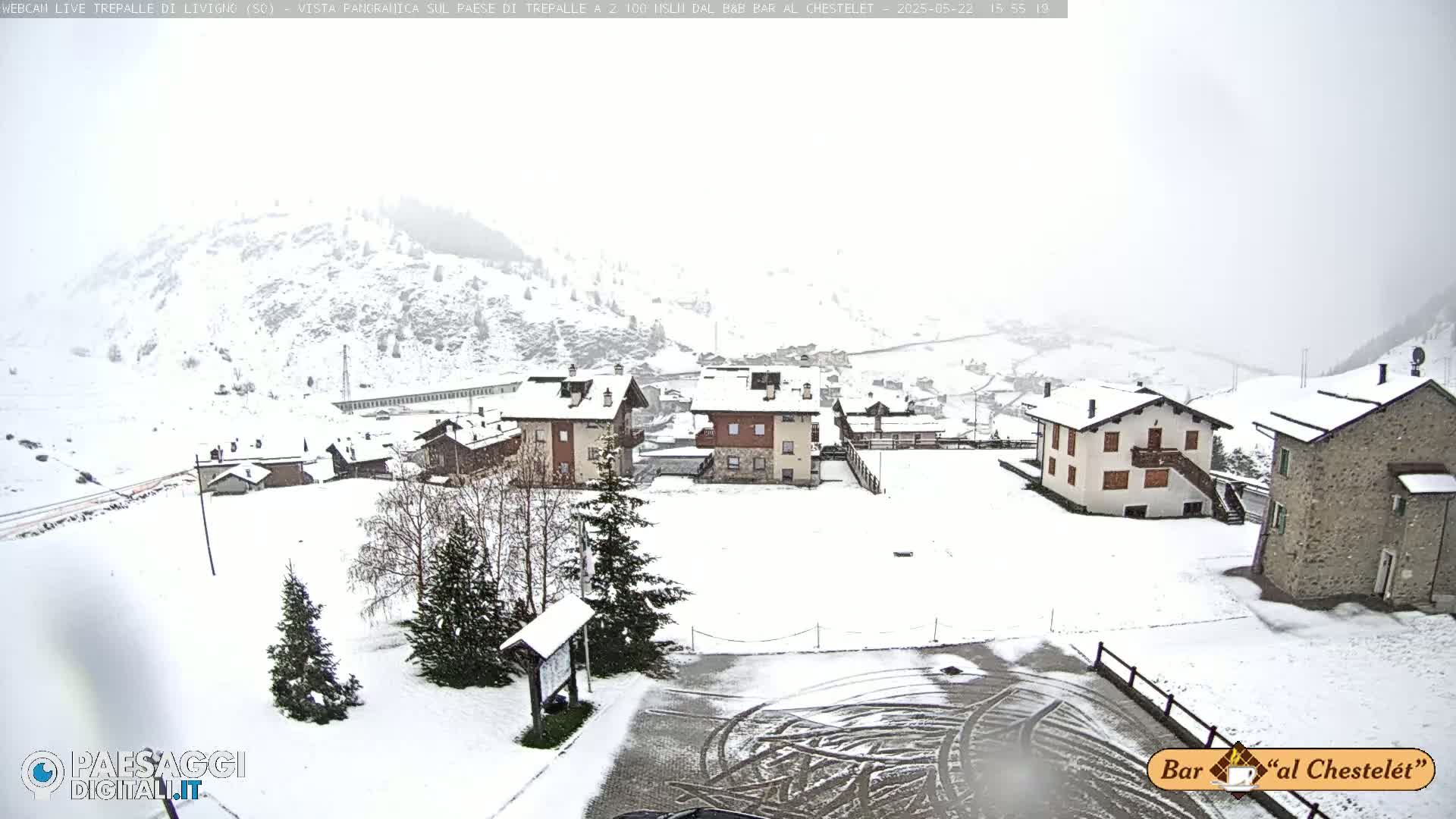 A snow-covered village nestled in a mountainous area, with light snowfall.