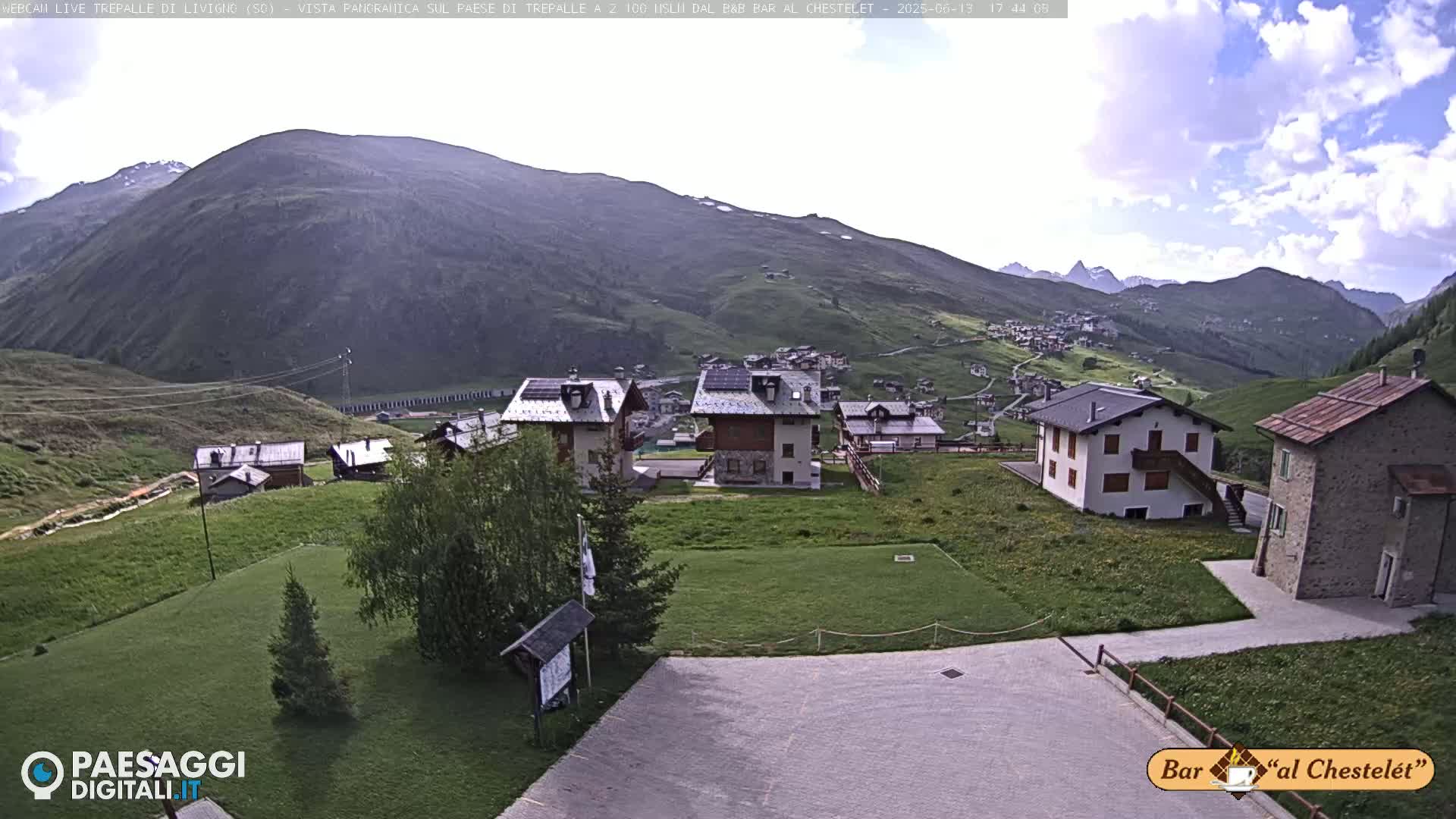 A small village nestled in a valley between mountains on a partly cloudy day.