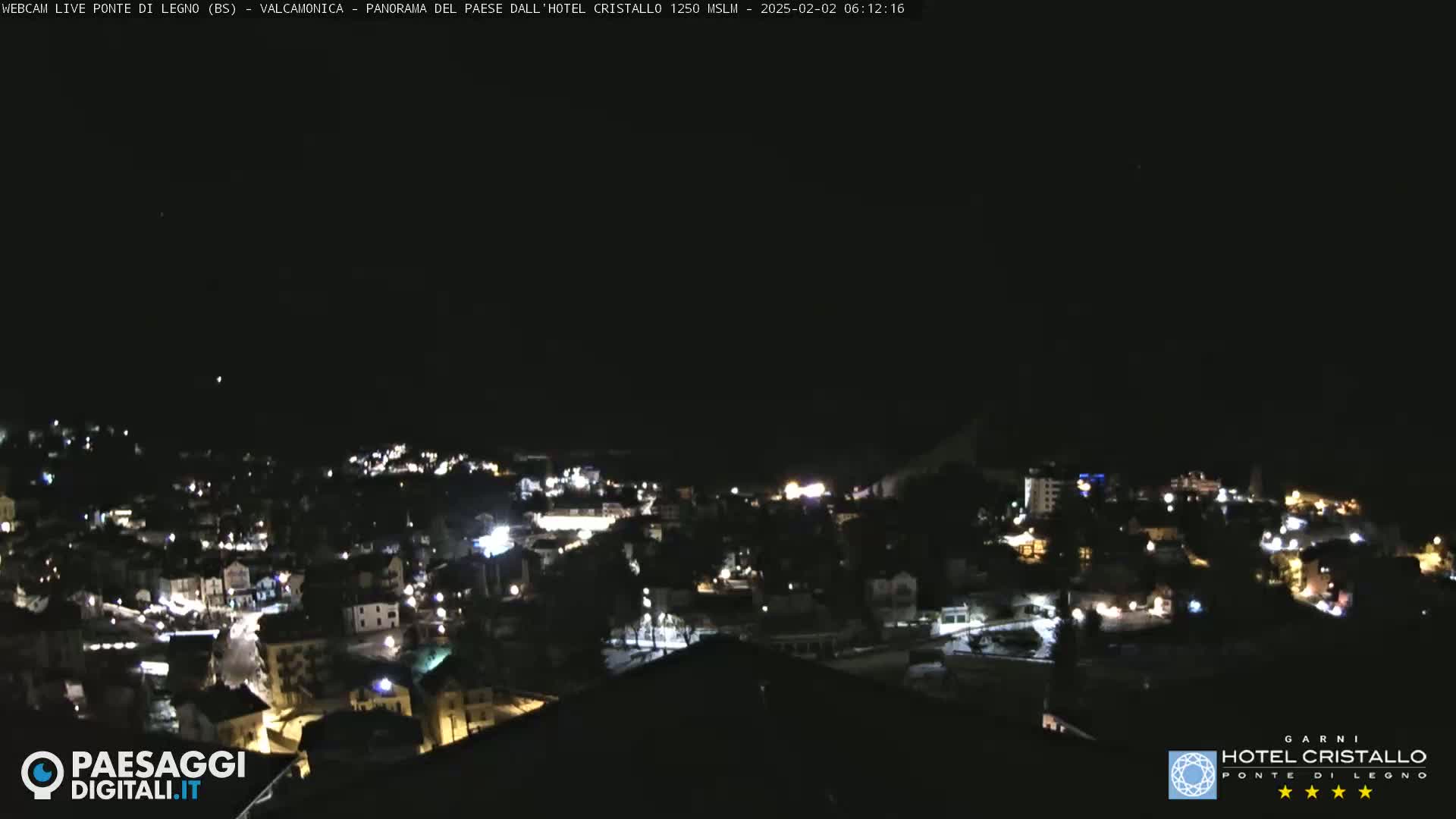 A nighttime view of a town illuminated by lights under a clear, dark sky.