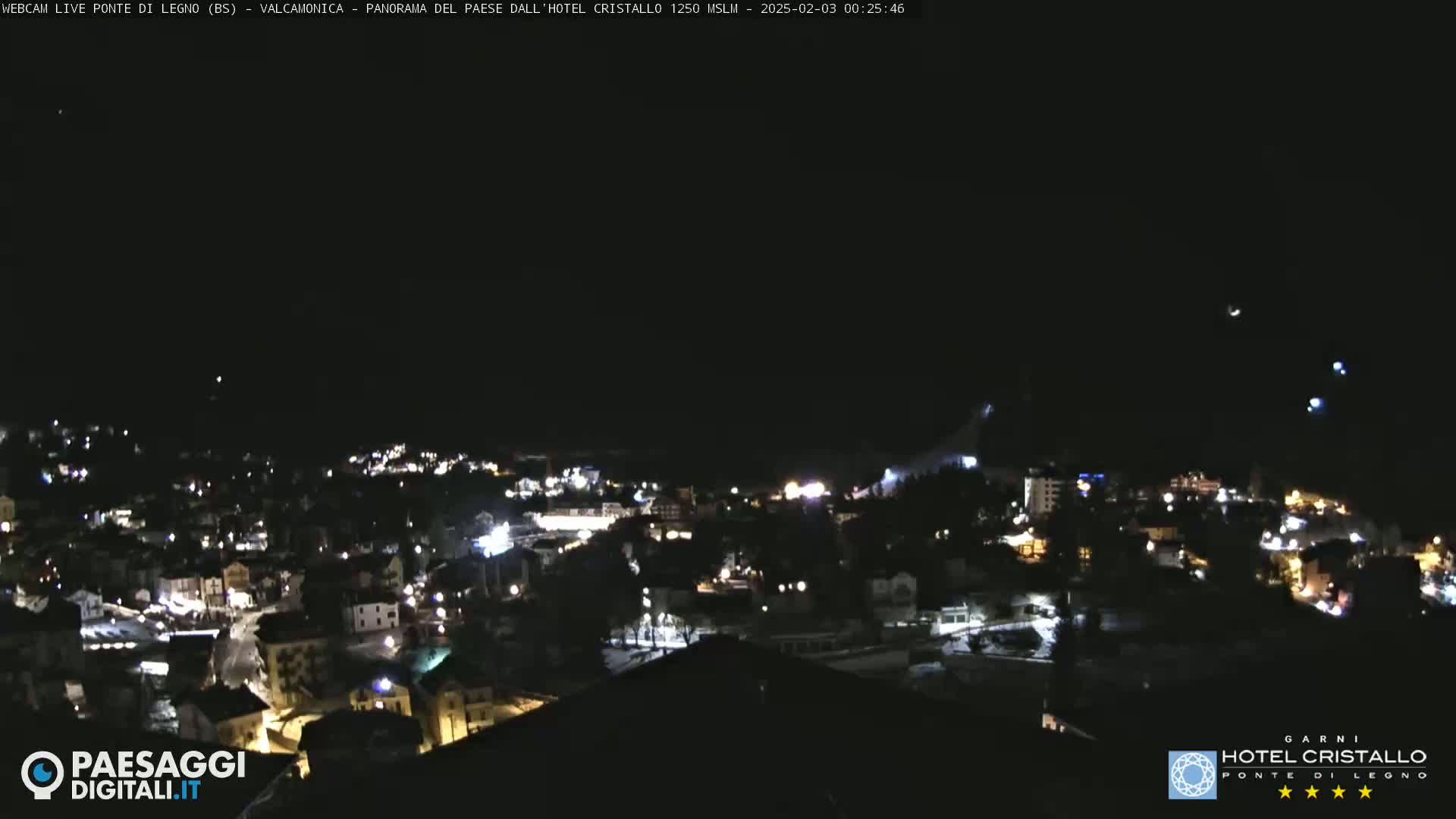 A nighttime, aerial view of a small town illuminated by lights, under a dark, clear sky.