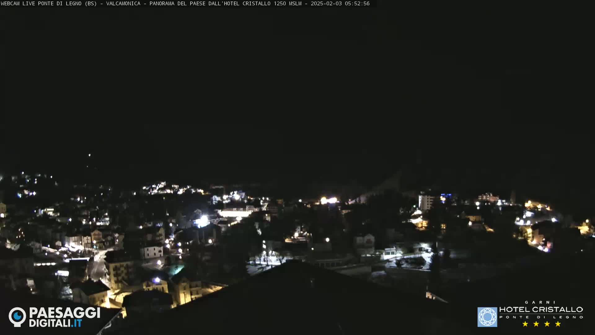 A nighttime, long-range view of a town illuminated by scattered lights under a dark sky.