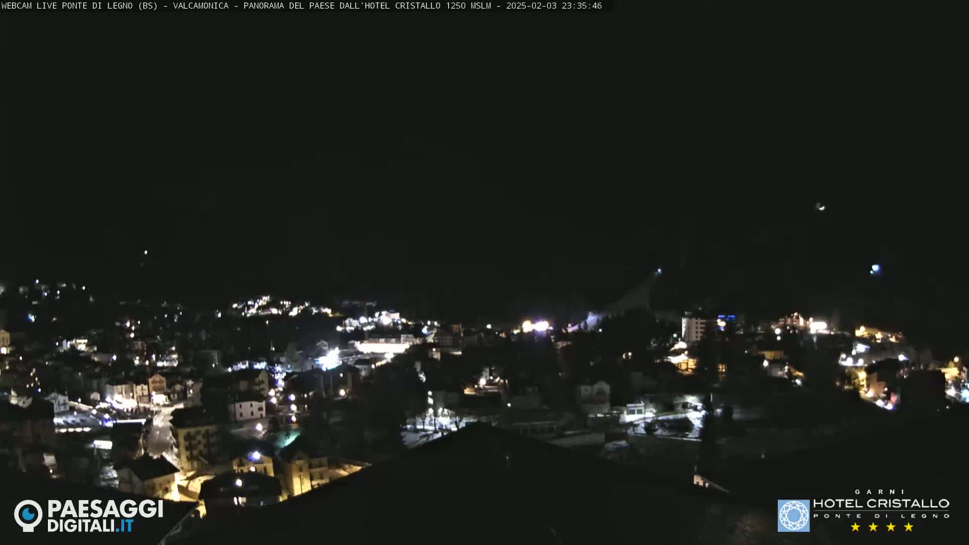 A nighttime, aerial view of a town illuminated by streetlights under a clear, dark sky.