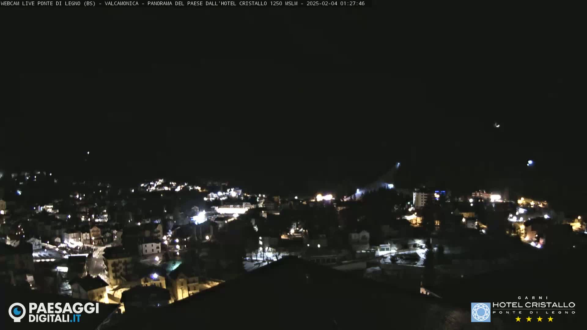 A nighttime, aerial view of a town illuminated by streetlights under a clear, dark sky.